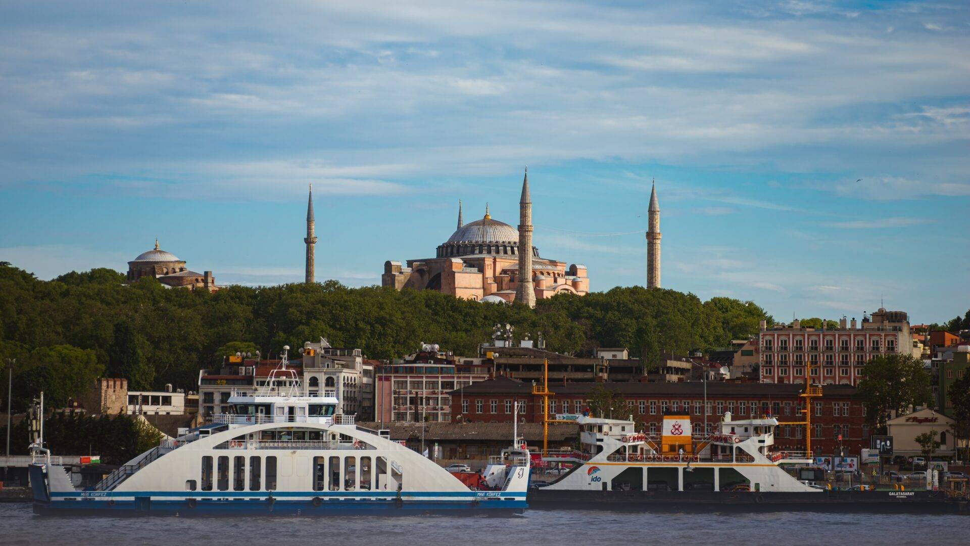 Due navi da crociera davanti a una grande moschea con cupole e minareti che dominano la città storica affacciata sul mare