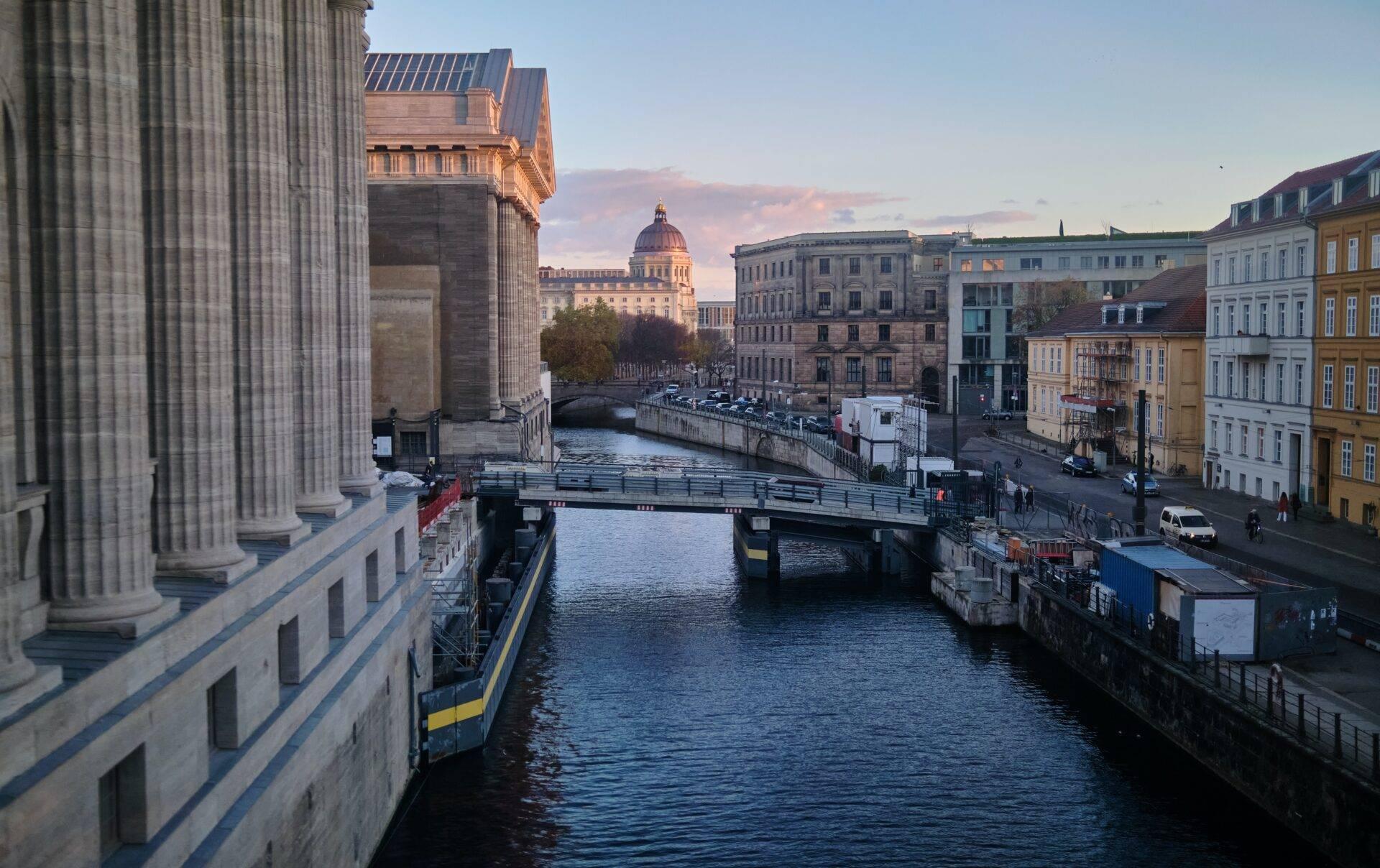Vista su un canale urbano con ponti, edifici storici e una cupola architettonica sullo sfondo