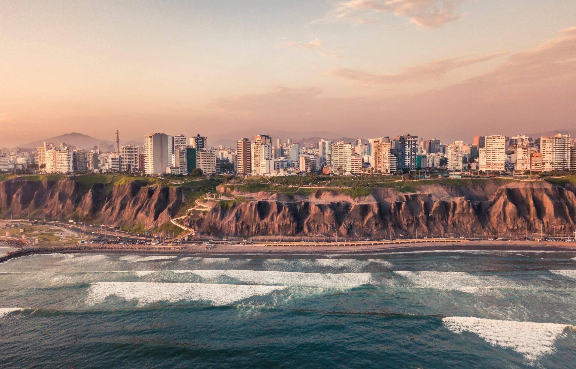 Vista costera de una ciudad moderna con acantilados ocre dominando una playa de arena y el océano Pacífico
