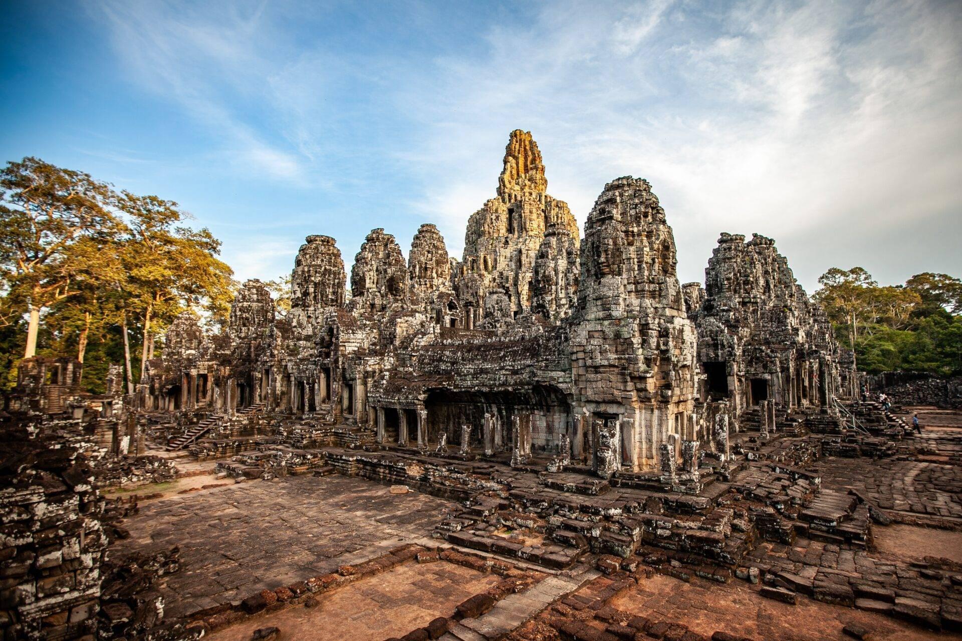Reise nach Kambodscha: Reisfelder und Tempel unter bewölktem Himmel
