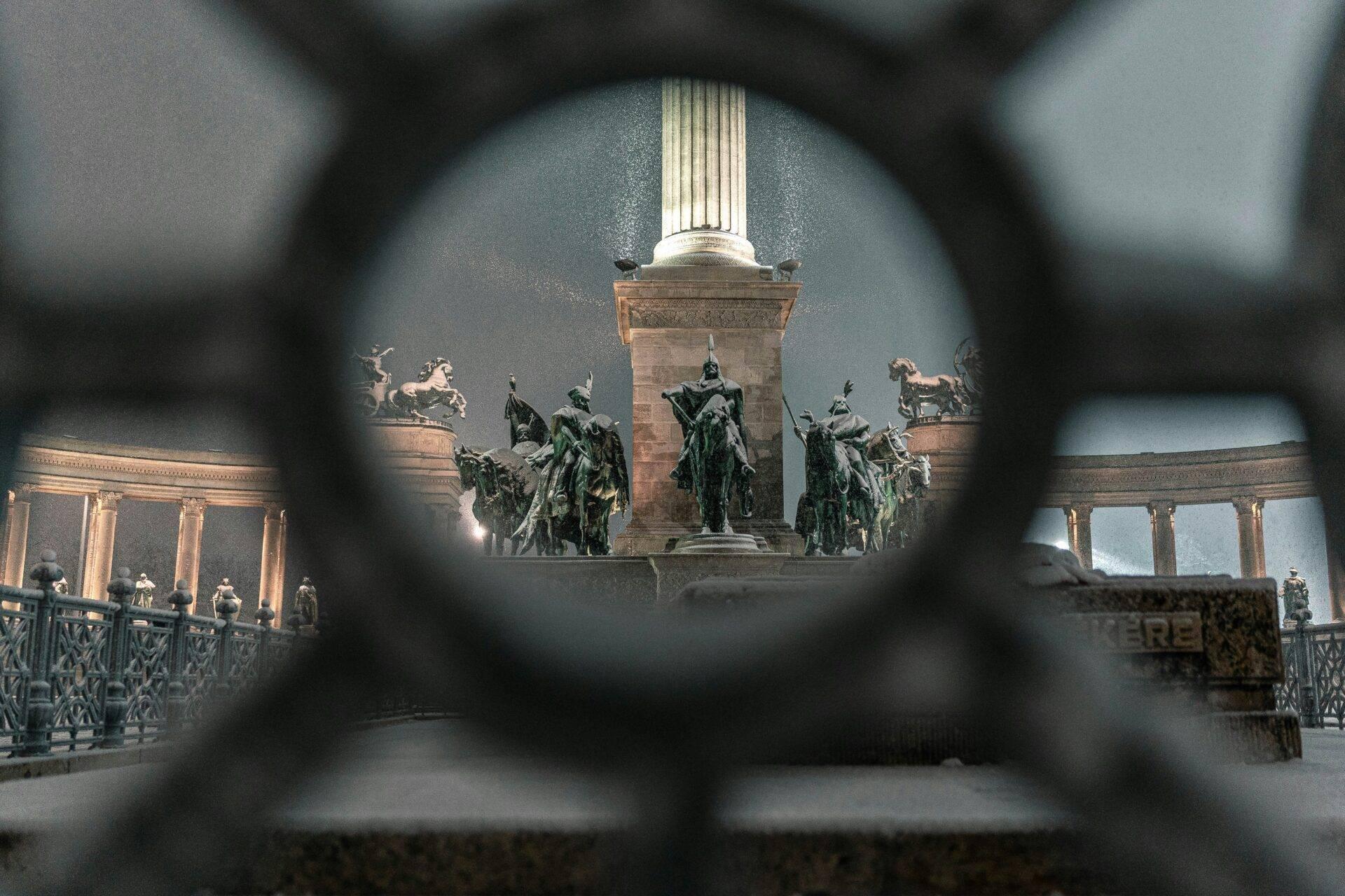 Vista a través de una verja de hierro del monumento a los héroes con estatuas ecuestres y columnata en Budapest