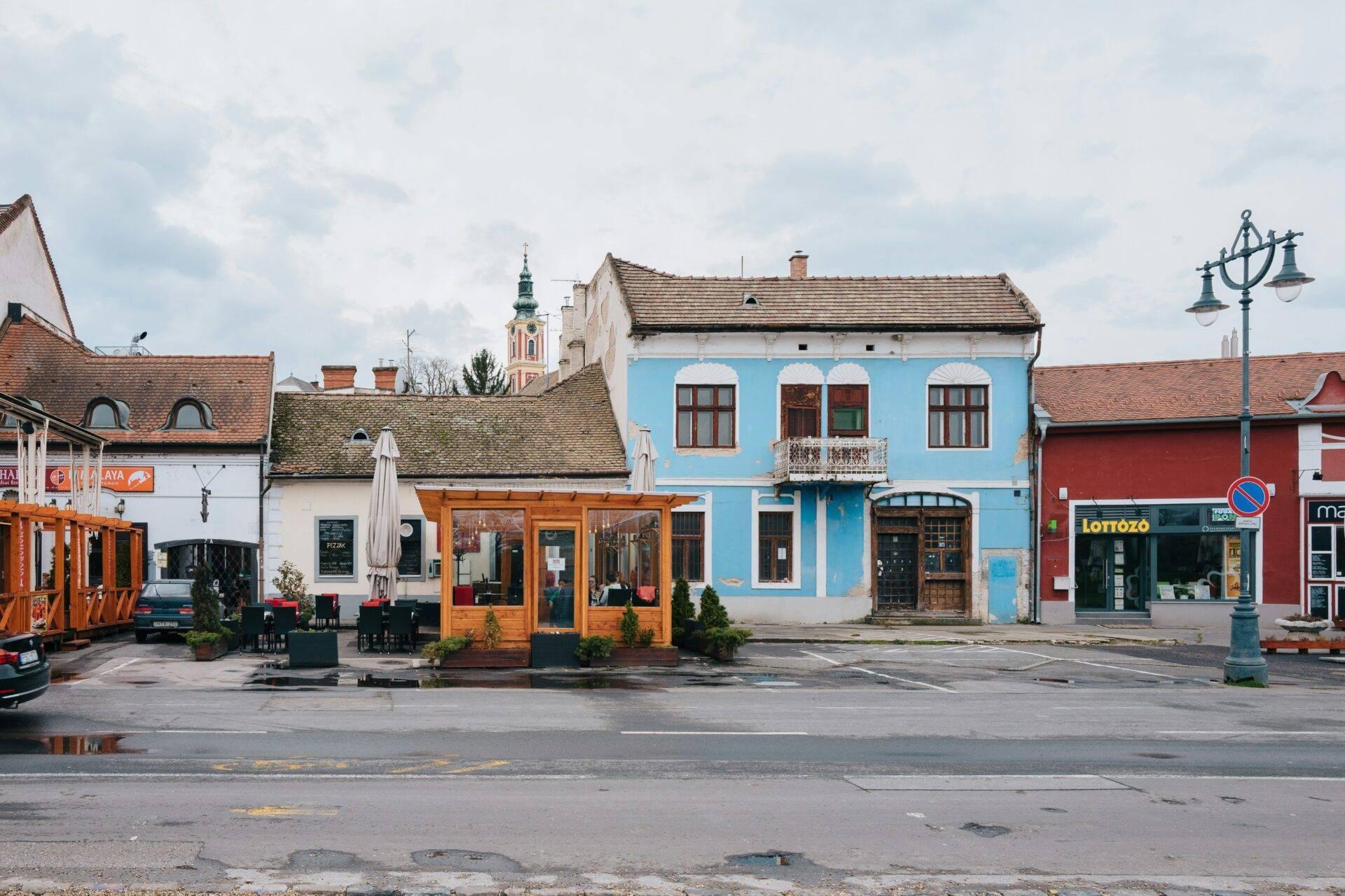 Una plaza de pueblo de Europa Central con casas de colores de fachadas azules y blancas e iglesia al fondo