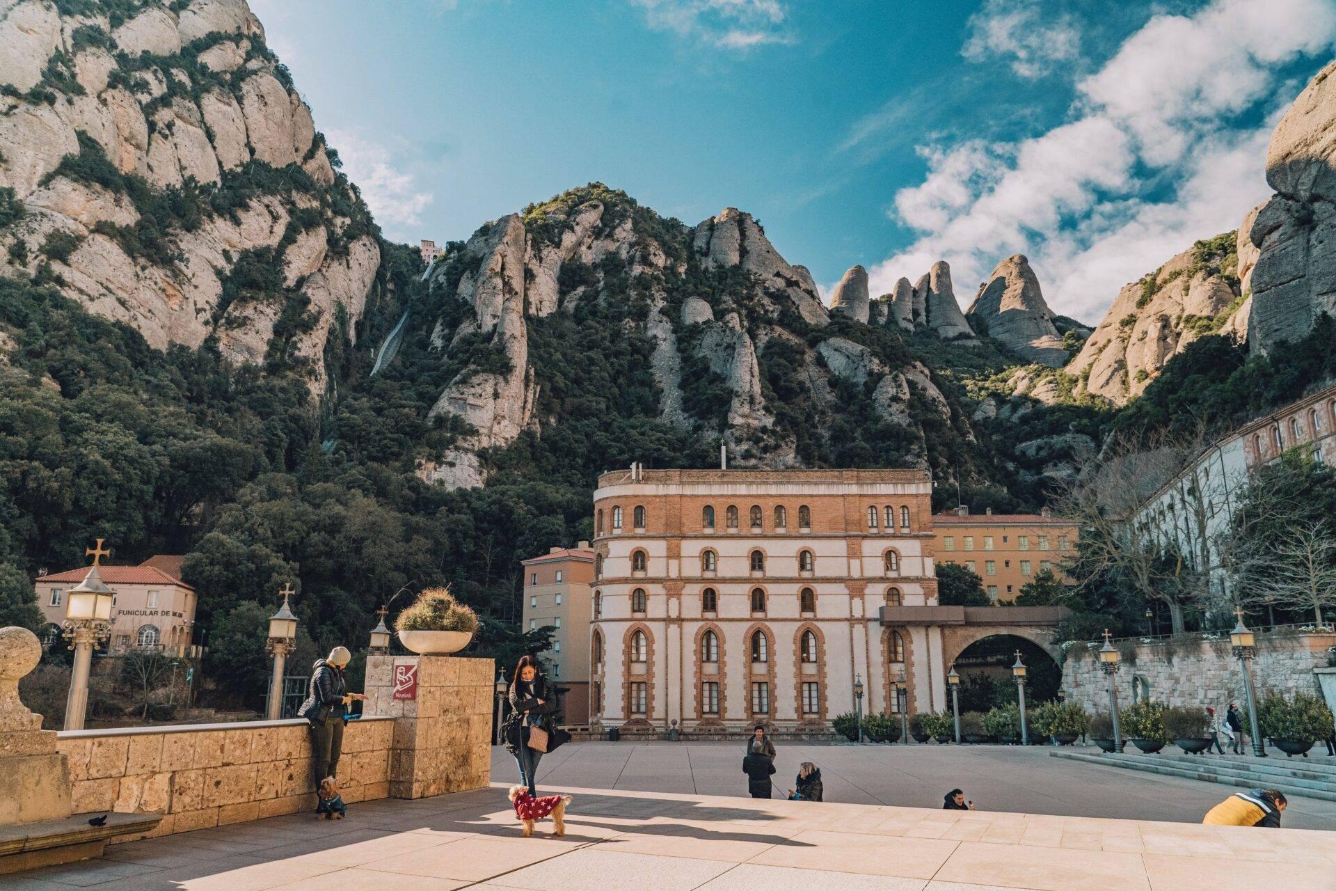 Un monastero in pietra rosa ai piedi di formazioni rocciose spettacolari in una valle montana