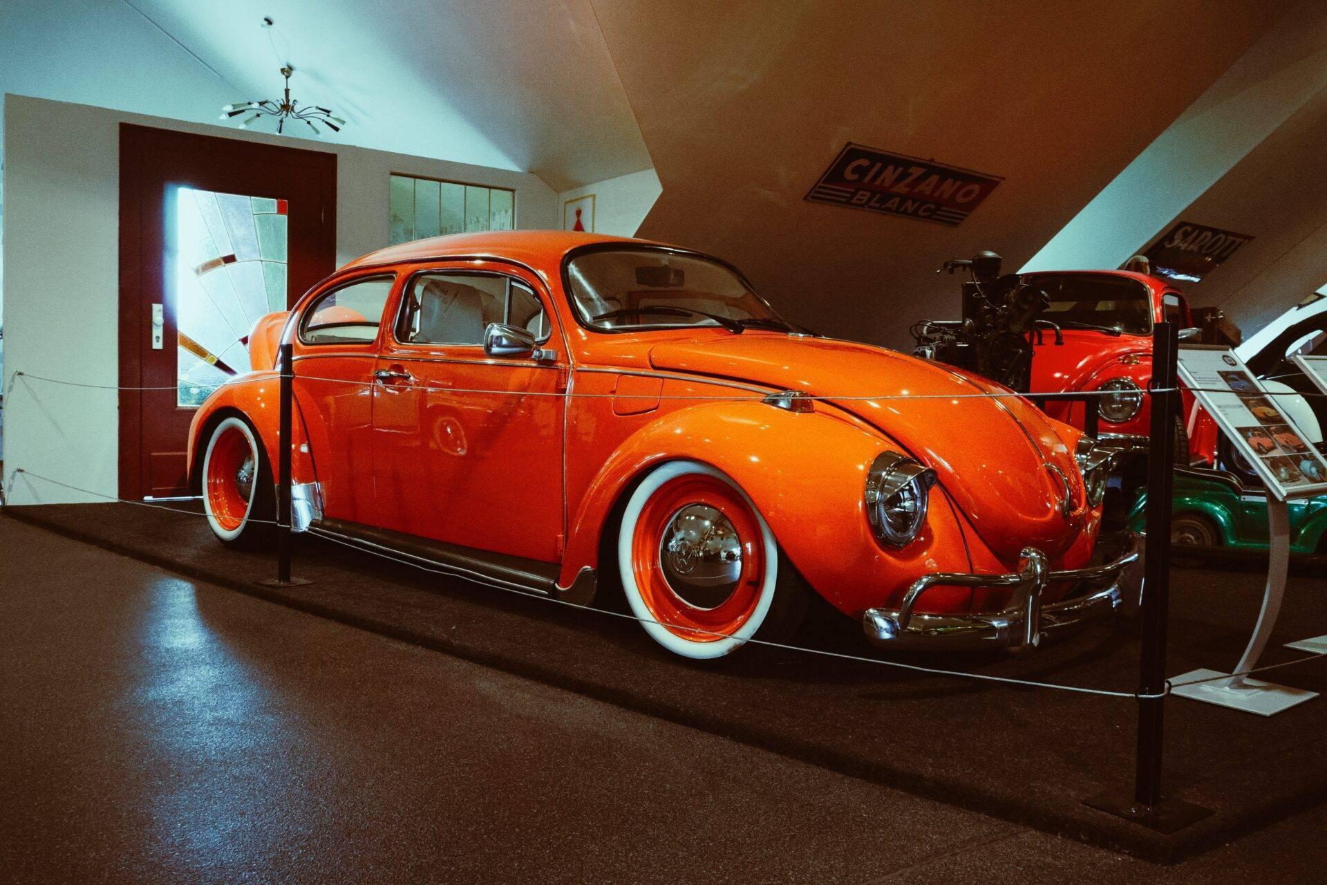Un maggiolino Volkswagen rosso restaurato esposto in un museo dell’auto al coperto