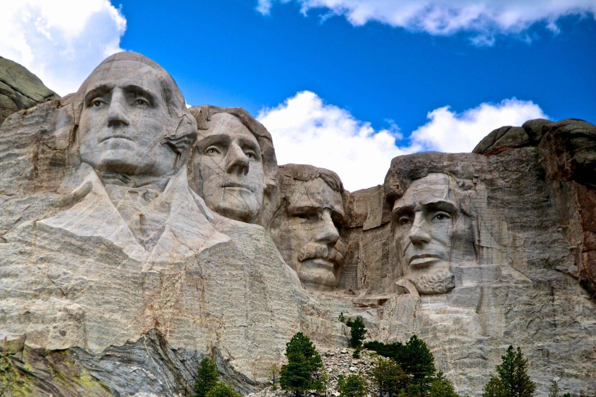 Die vier gemeißelten Gesichter am Mount Rushmore in den Bergen von South Dakota unter blauem Himmel