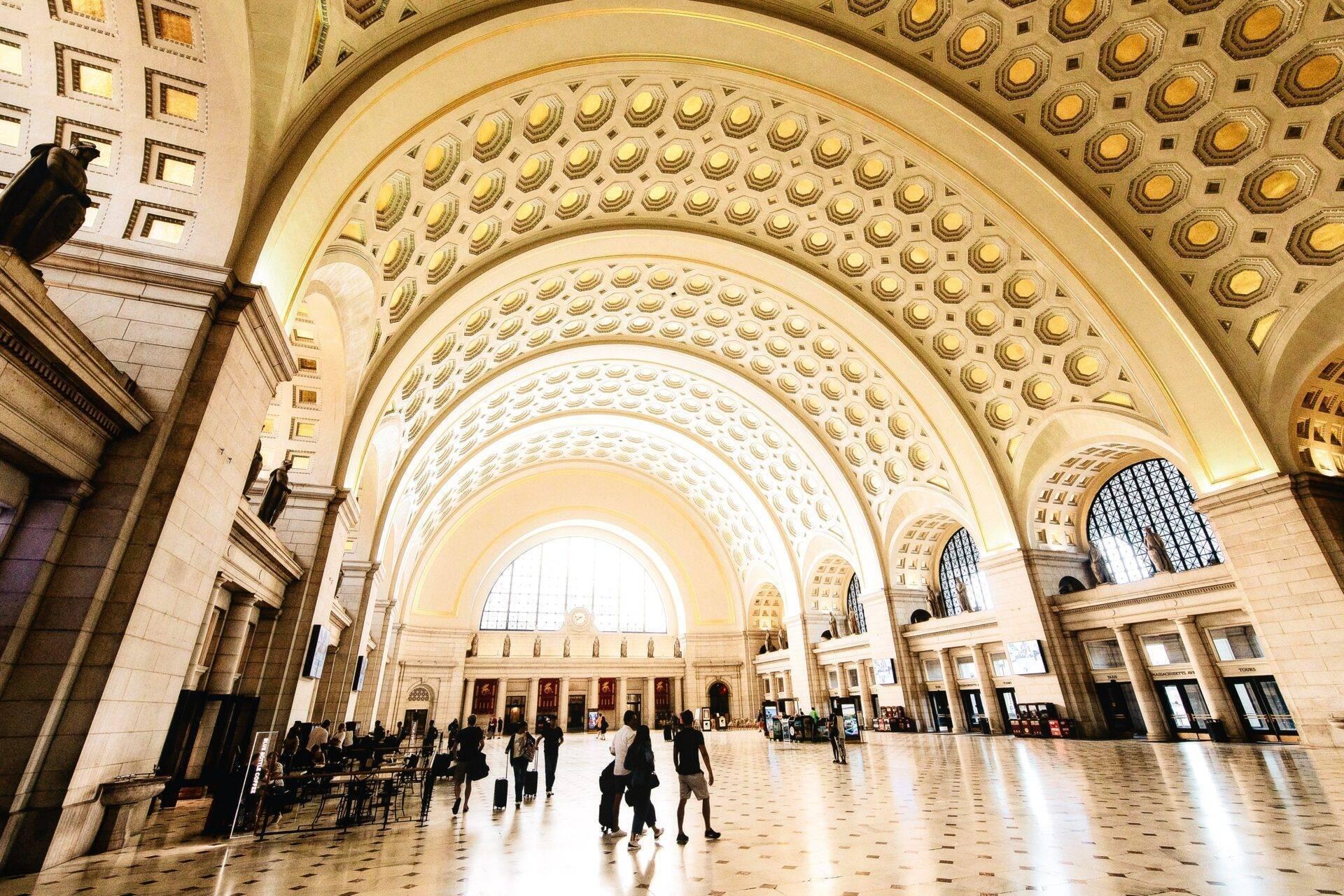 Eine monumentale Halle mit vergoldeten Ziergewölben und konzentrischen Bögen, die Besucher in eindrucksvoller klassischer Architektur empfängt