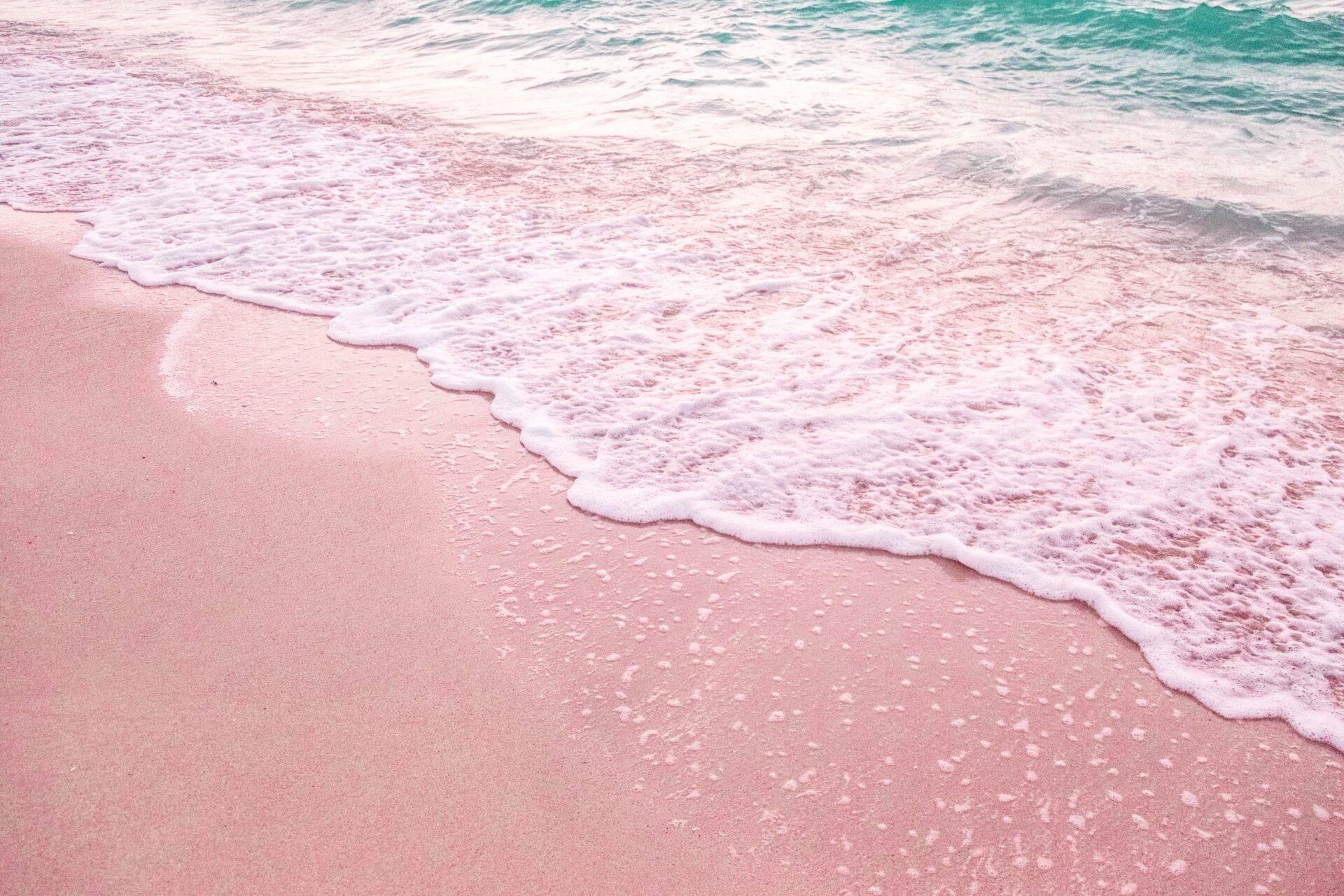 Olas turquesas rompiendo sobre una playa de arena rosa fina en Bahamas