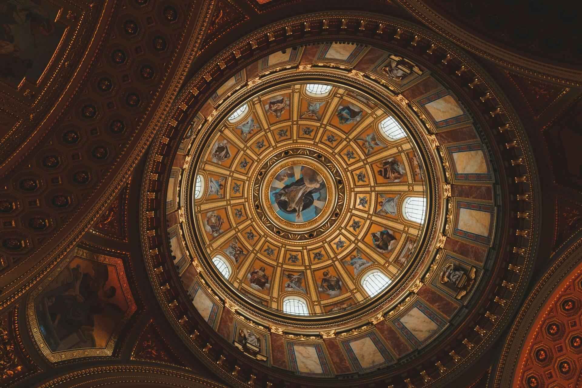 Vista cenital de una cúpula circular ricamente ornamentada con frescos, dorados y óculo luminoso en arquitectura neoclásica