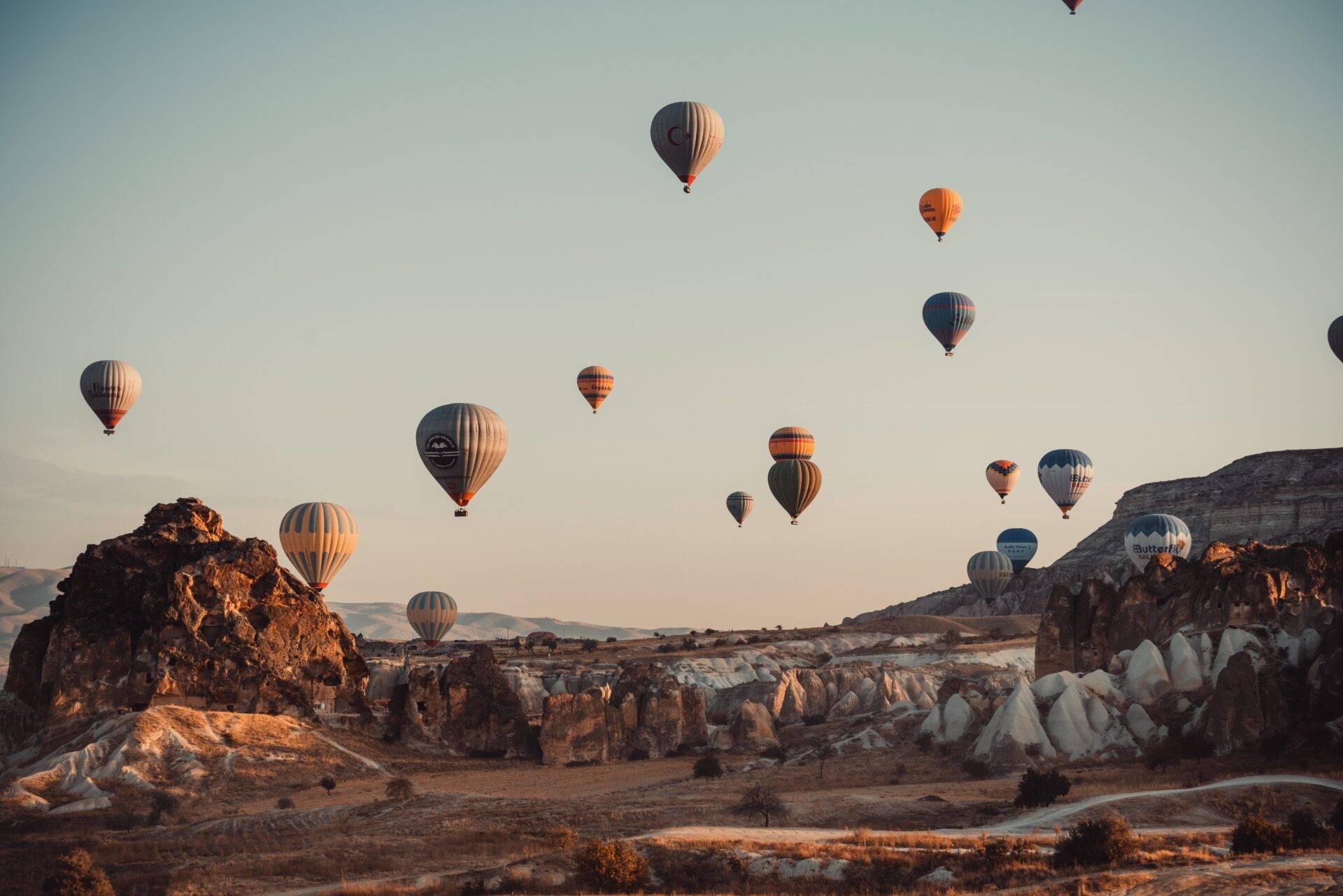 Diverse mongolfiere colorate sorvolano formazioni rocciose di pietra chiara all’alba