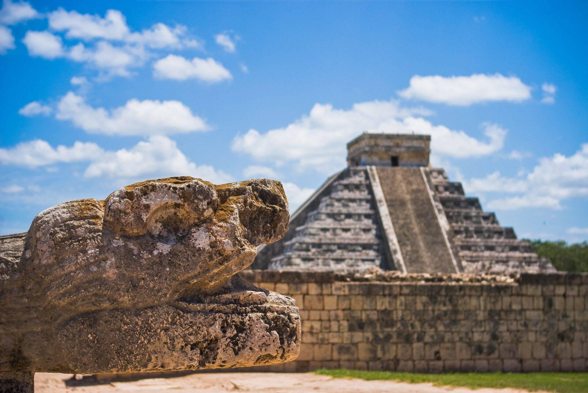 Rucksackreisender vor einem Maya-Tempel in Mexiko unter blauem Himmel