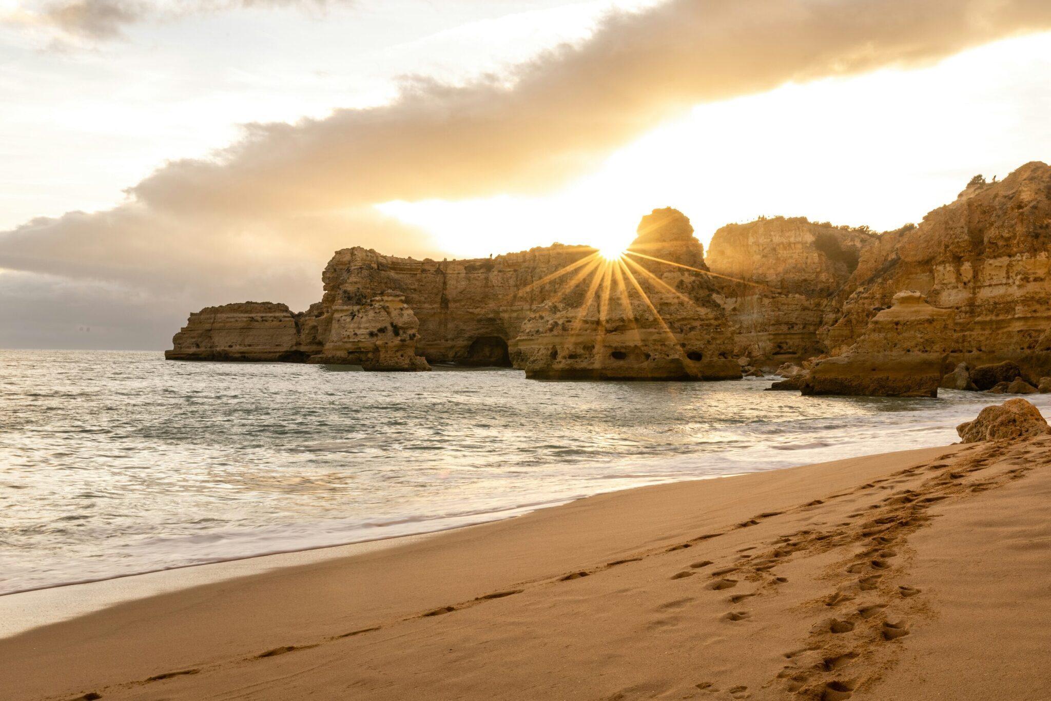 Goldener Strand mit spektakulären Felsformationen und Abendsonne, die den Ozean und die geologischen Strukturen beleuchtet