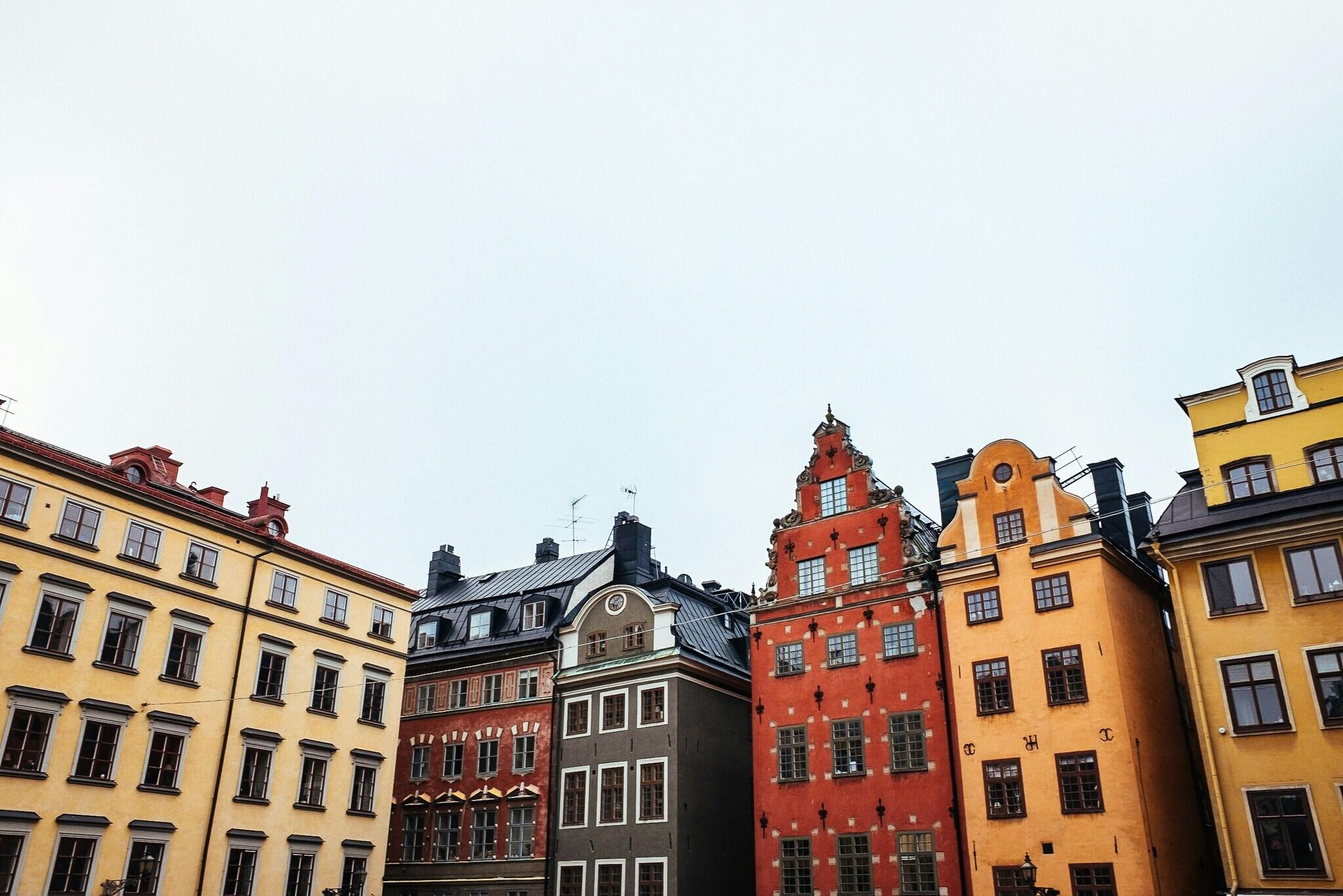 Fachadas coloridas de edificios históricos nórdicos alineados en una plaza adoquinada bajo un cielo despejado