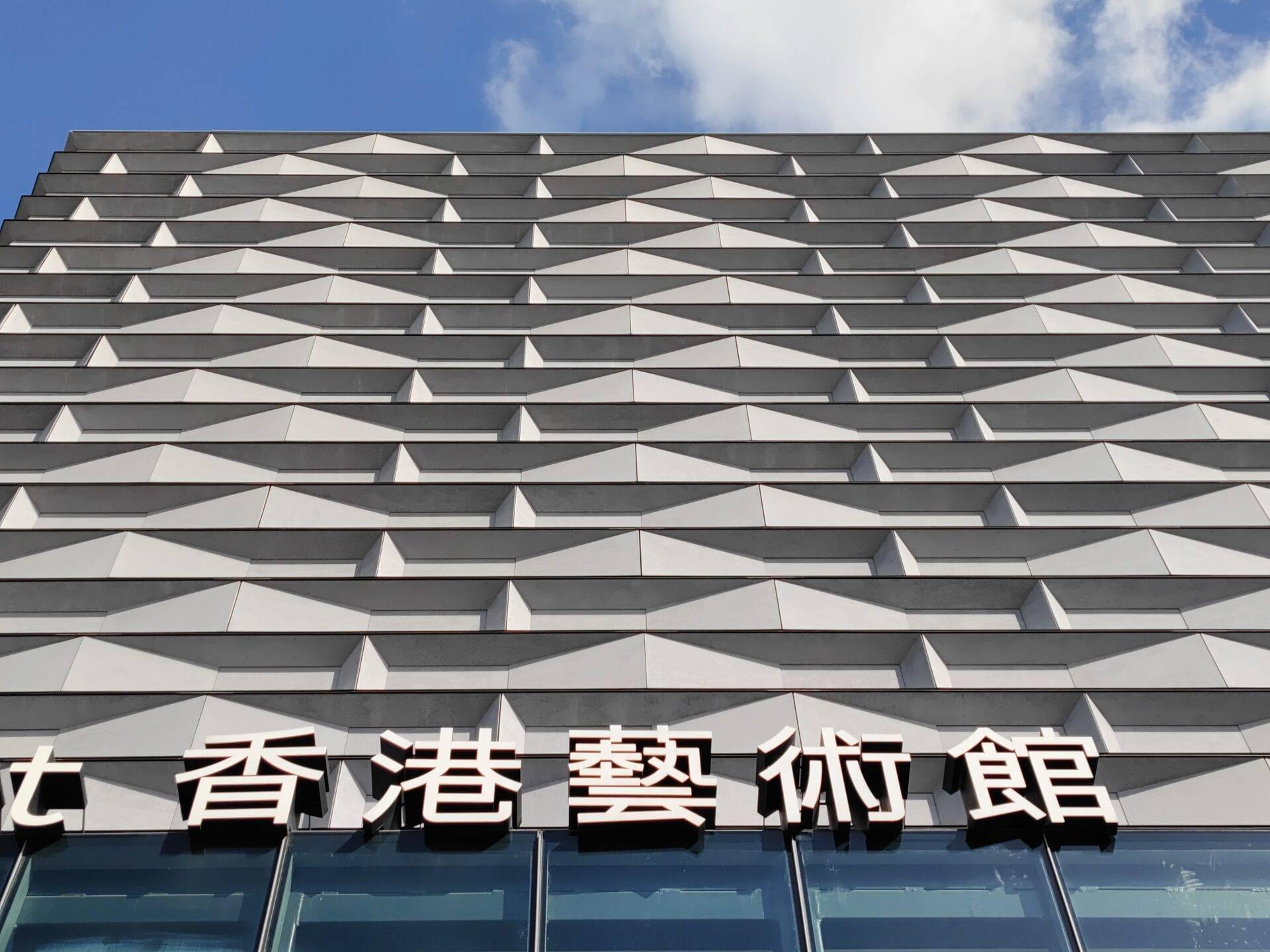 Moderne Museumsfassade in Hong Kong mit chinesischen Schildern und geometrisch gewelltem Design