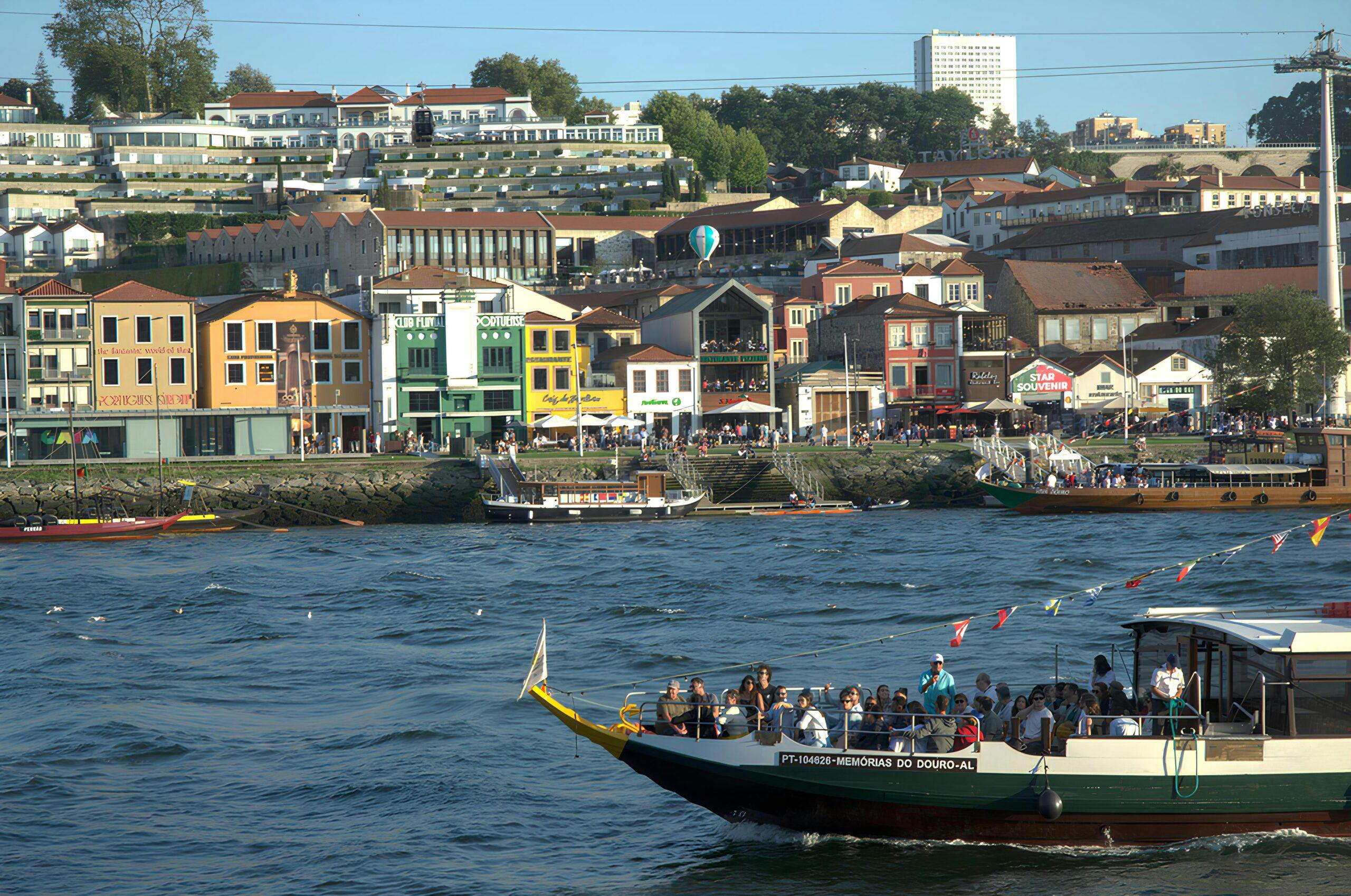 Un barco turístico de vivos colores navega por el río frente a pintorescas fachadas en un animado paseo fluvial