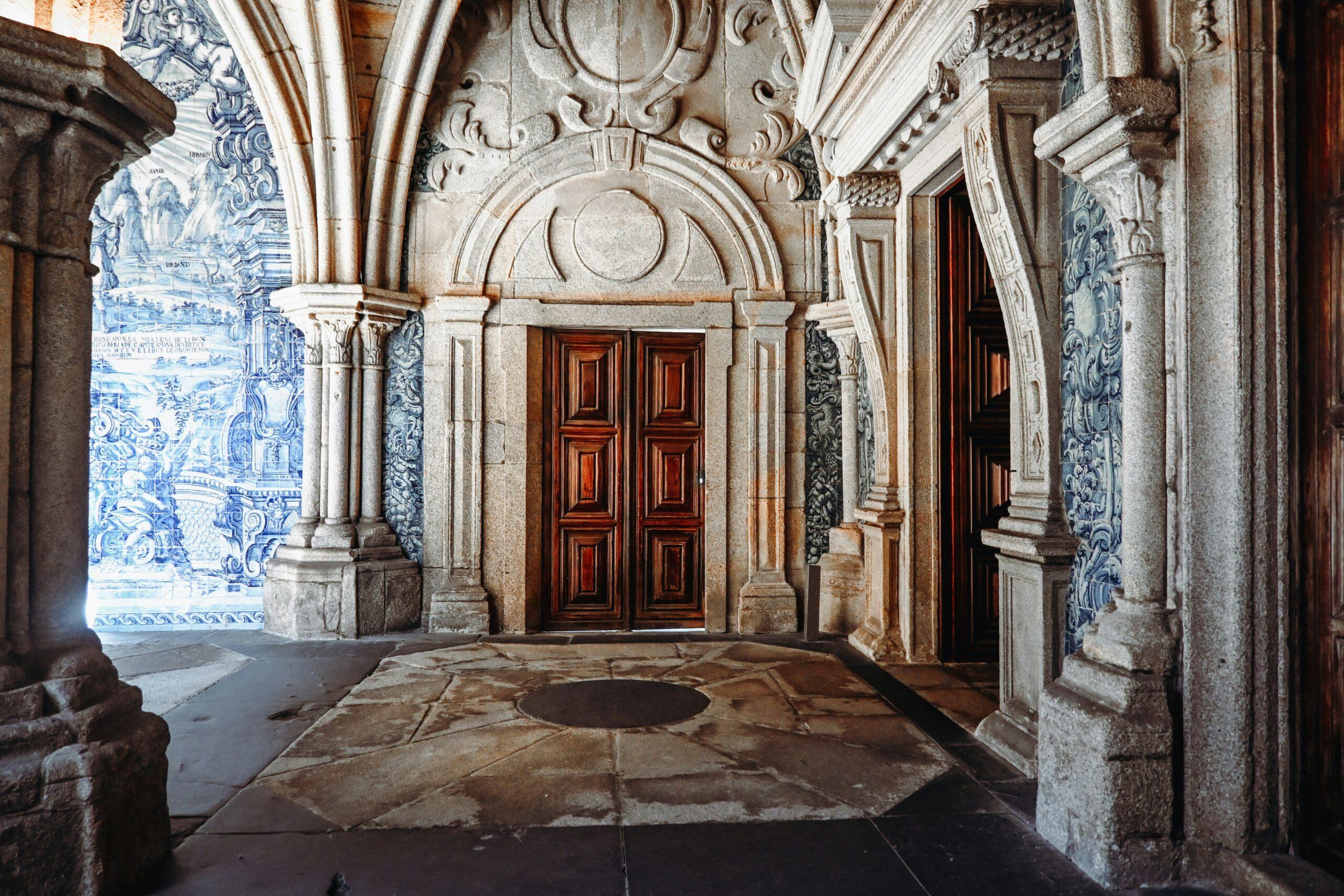 Corredor barroco decorado con azulejos portugueses azules y puertas de madera roja, con columnas de piedra tallada