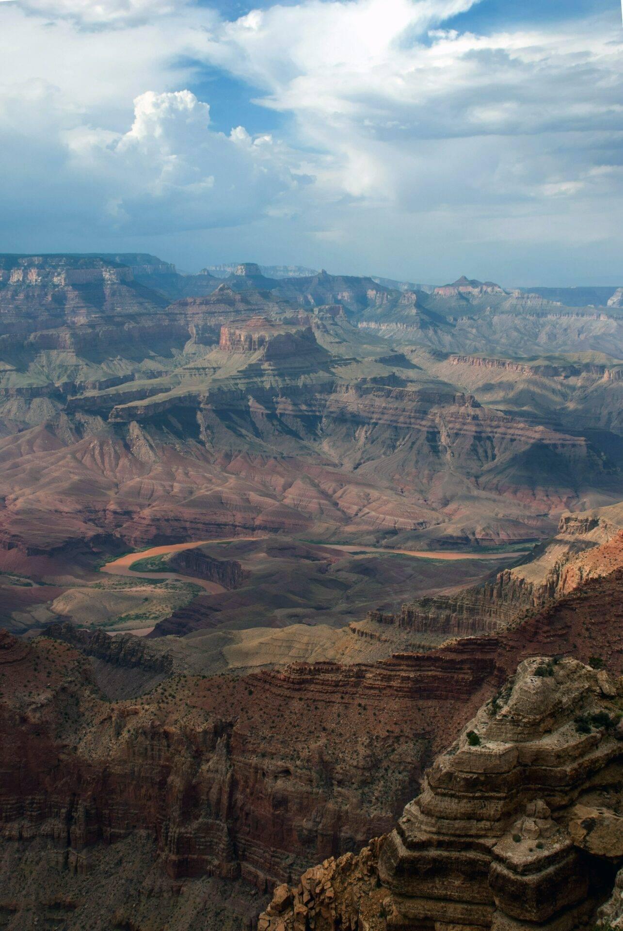 Luftaufnahme eines riesigen Canyons mit geschichteten roten und braunen Klippen und einem mäandernden Fluss am Grund