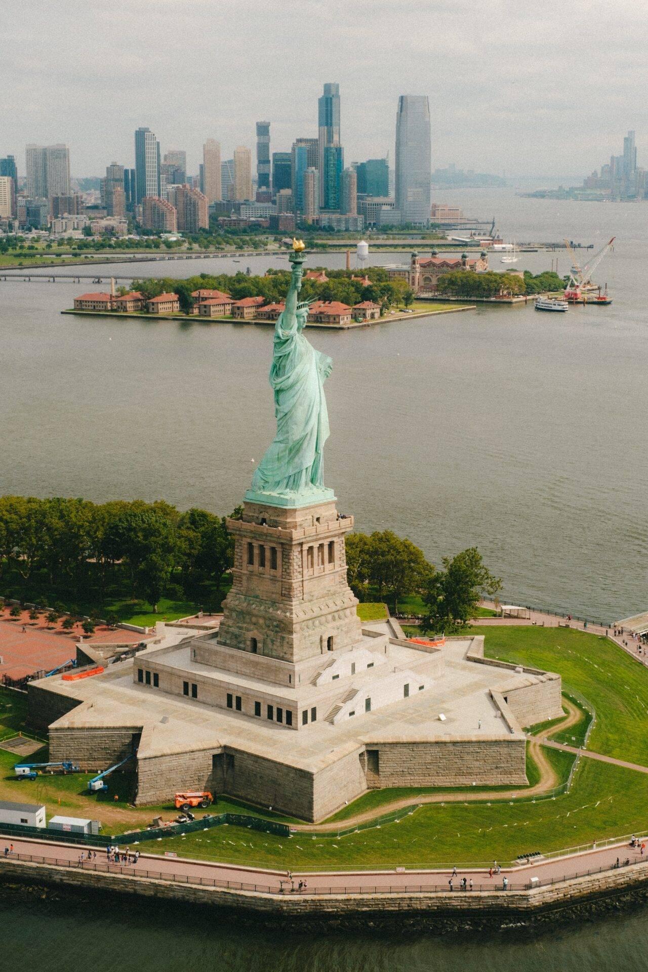 Die Freiheitsstatue auf ihrer Insel mit Manhattan und seinen Wolkenkratzern im Hintergrund