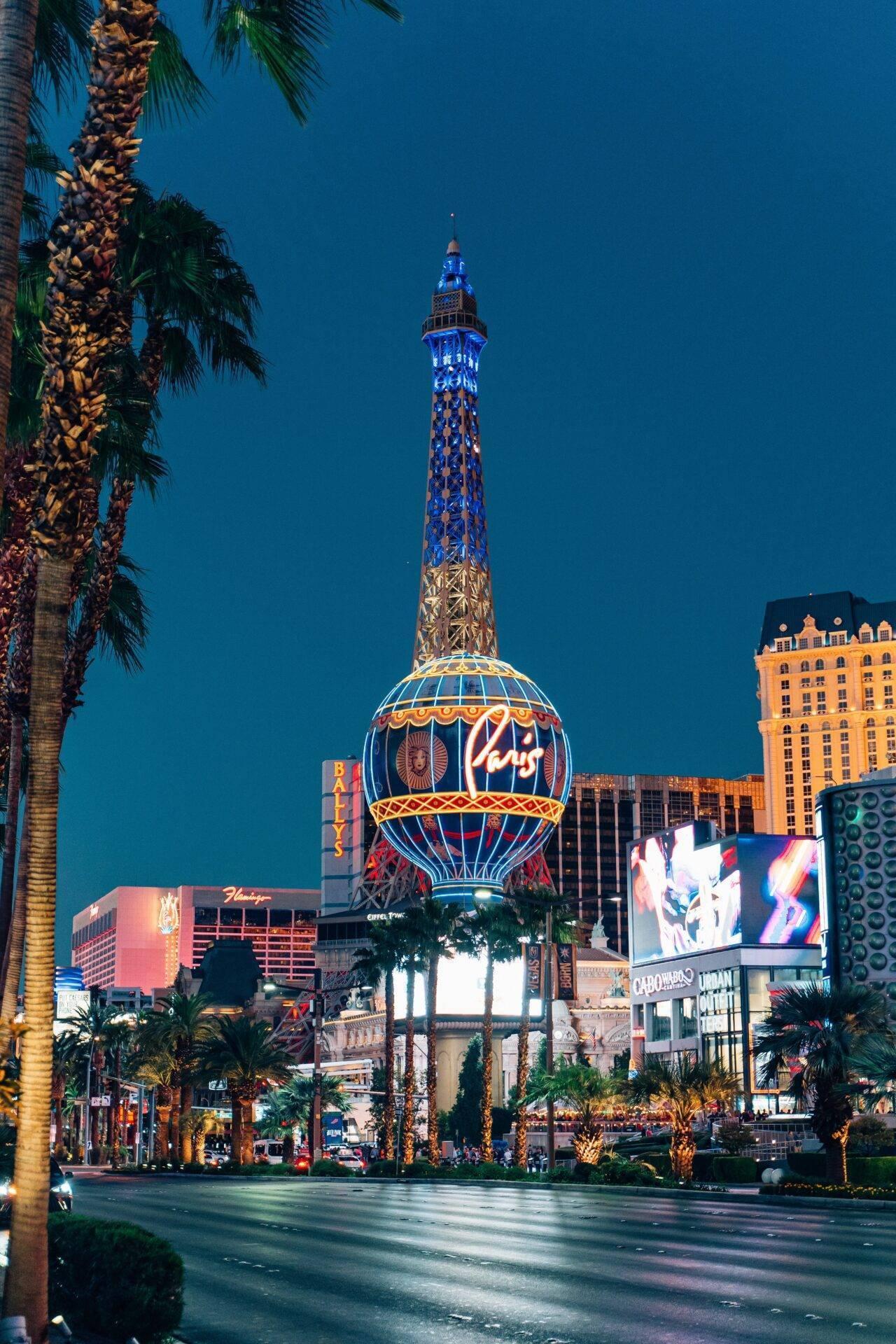 Nächtlicher Blick auf eine berühmte Touristenmeile mit illuminiertem blauem Turm und Casinogebäuden entlang der Avenue