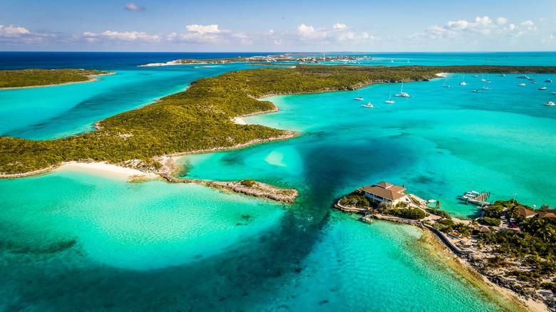 Vista aerea di un arcipelago tropicale con acque turchesi cristalline, isole boscose, spiagge bianche e barche all’ancora