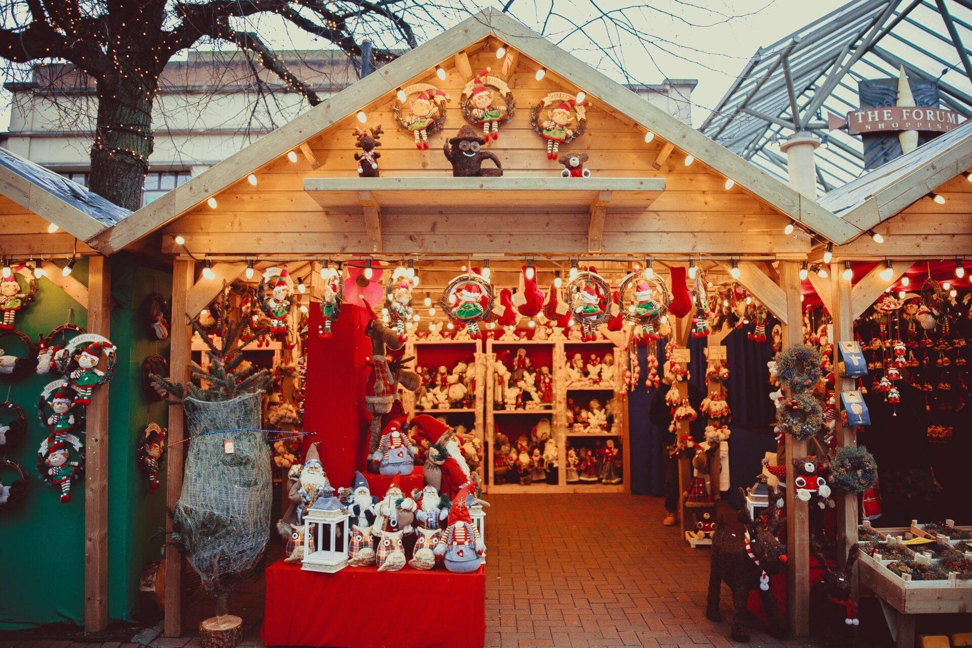 Una caseta de madera en un mercado de Navidad europeo repleta de decoraciones y figuras festivas en rojo y oro