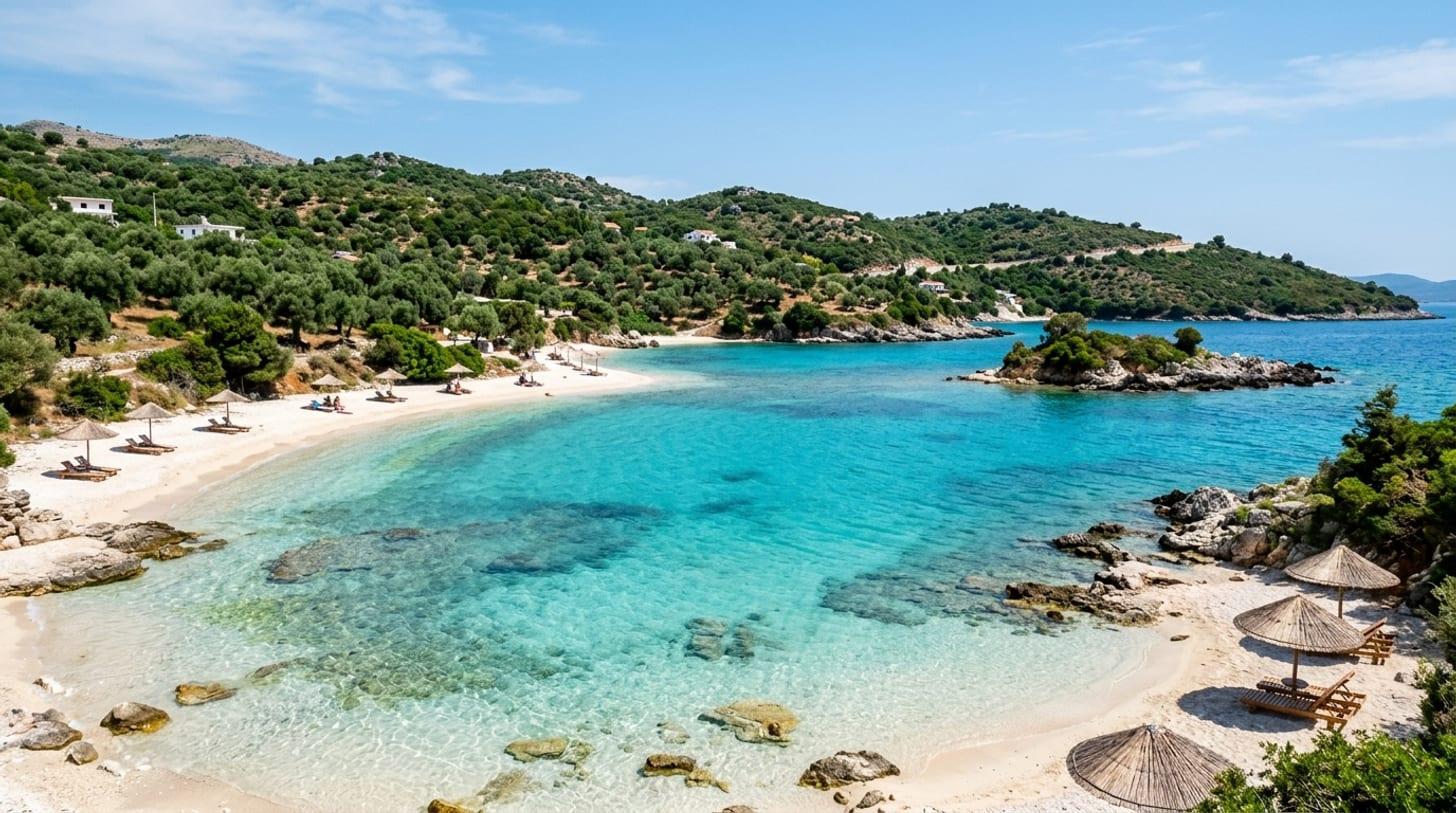 Caletta della Riviera albanese vicino a Ksamil, acqua turchese trasparente, sabbia bianca e colline di ulivi