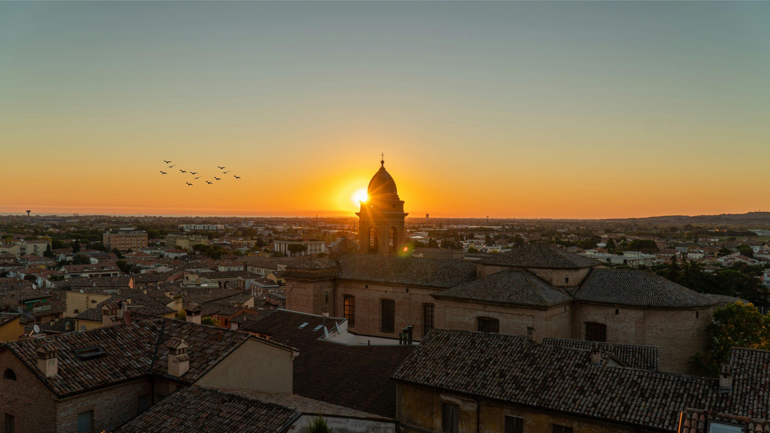 Atardecer sobre una catedral de cúpula dorada que domina los tejados de una ciudad italiana histórica