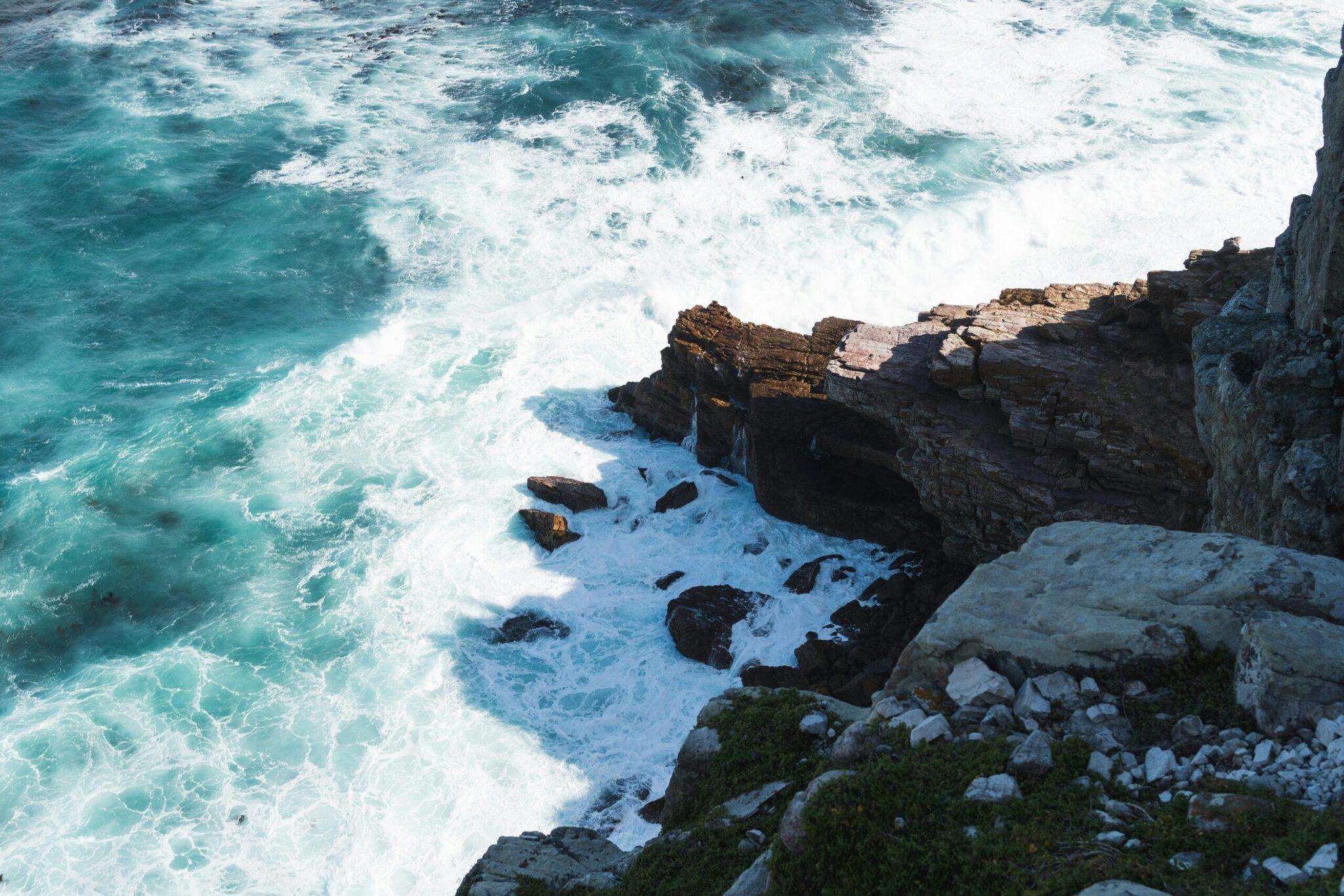 Onde turchesi che si infrangono contro scogliere rocciose a picco sull’oceano
