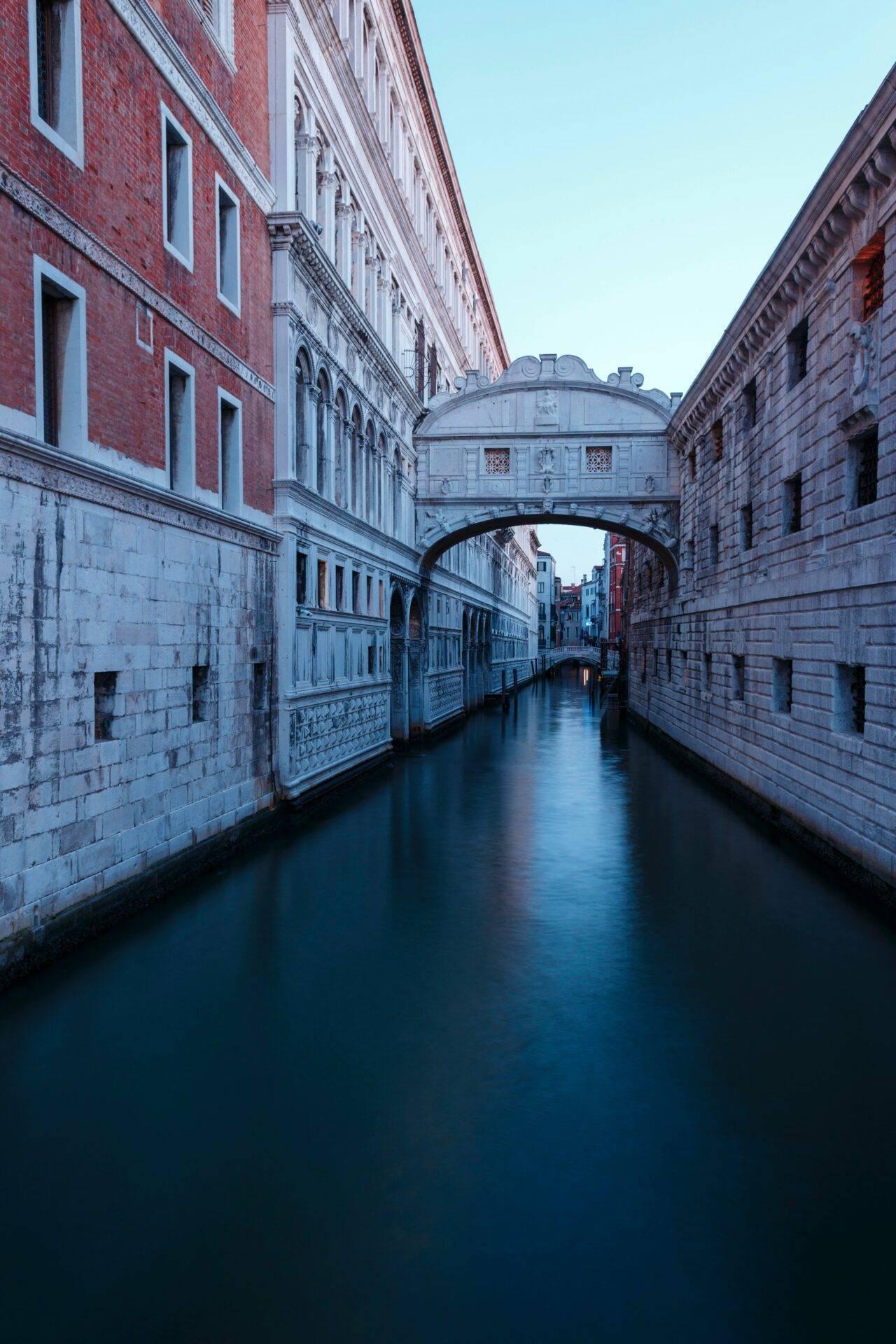 Un canale veneziano al tramonto con il celebre Ponte dei Sospiri che collega due palazzi storici in pietra