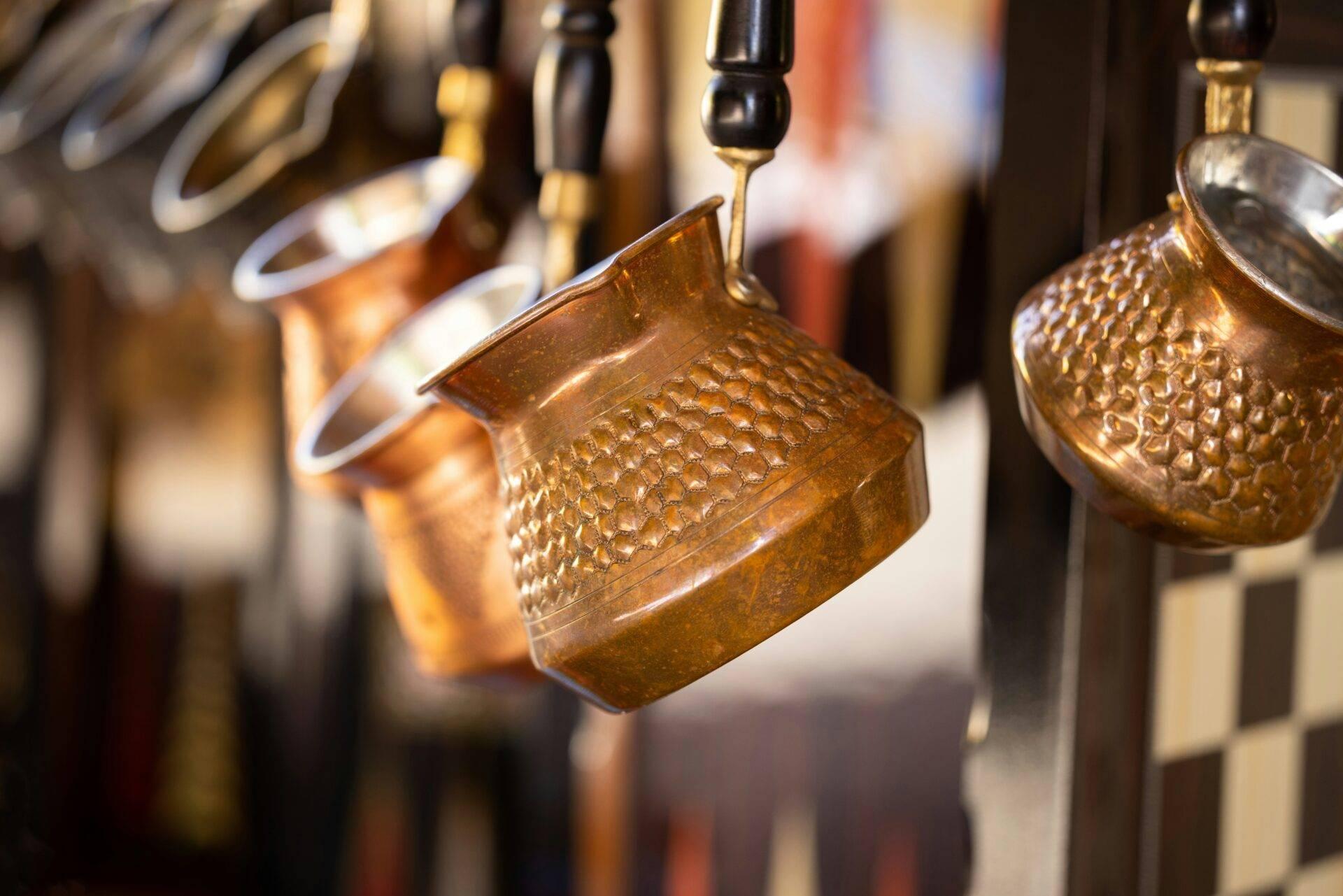 Jarras de cobre repujado colgadas, artesanía tradicional expuesta en un mercado o tienda artesanal