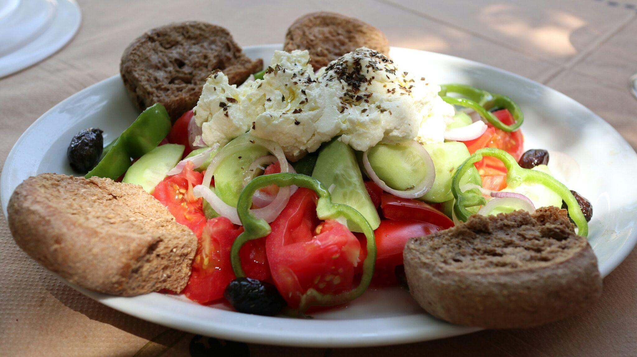 Teller mit mediterranen Mezze mit Hummus, Vollkornbrot, Gurke, Tomate und schwarzen Oliven
