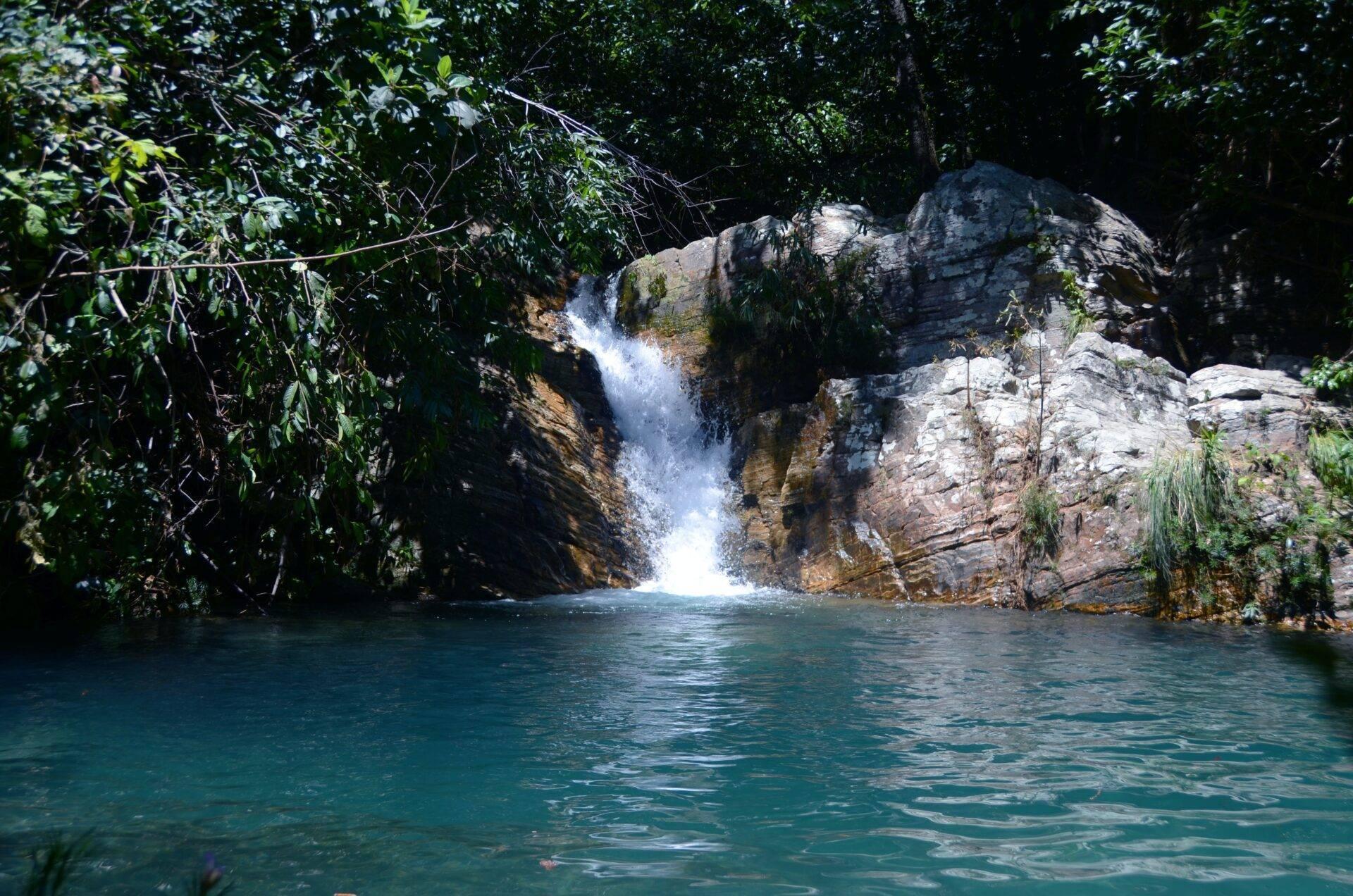Kristallklarer Wasserfall ergießt sich in ein türkisfarbenes Becken zwischen Felsenwänden und üppiger tropischer Vegetation