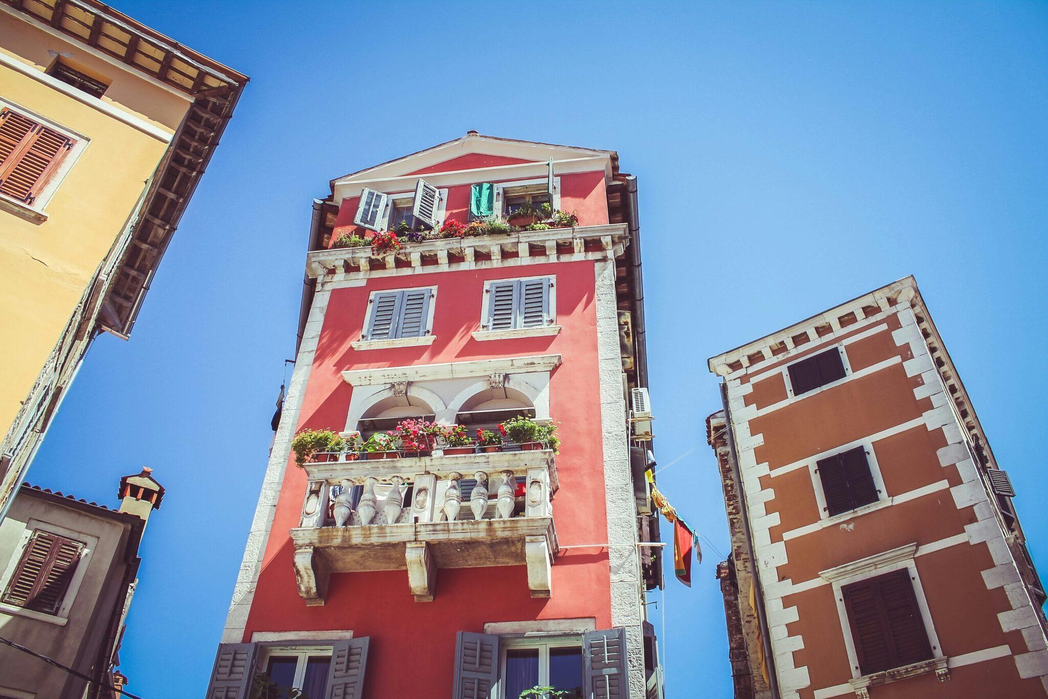 Facciate colorate di edifici mediterranei con balconi fioriti sotto un cielo azzurro