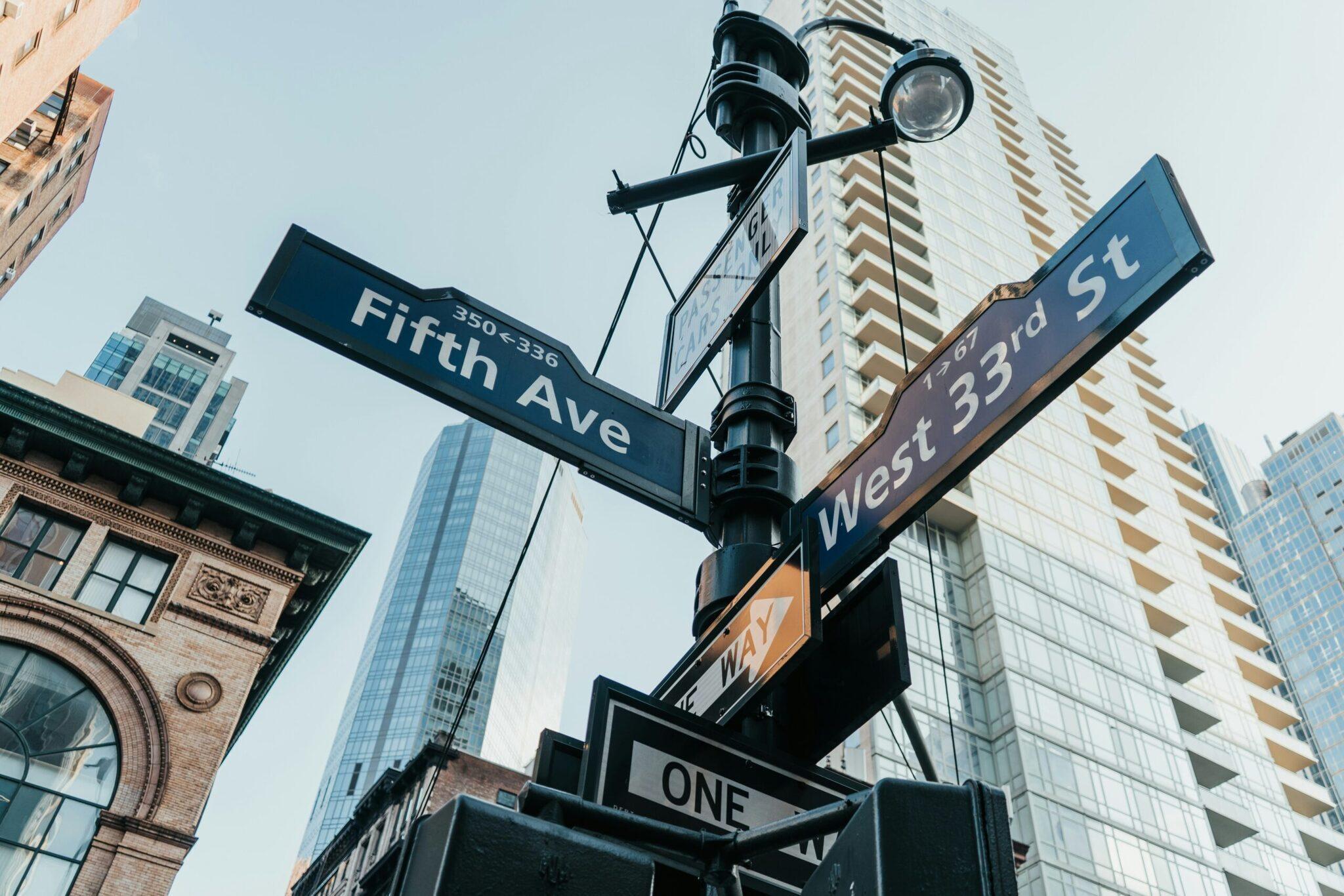 New York street corner with Fifth Avenue and West 33rd Street signs, modern buildings and historic architecture side by side