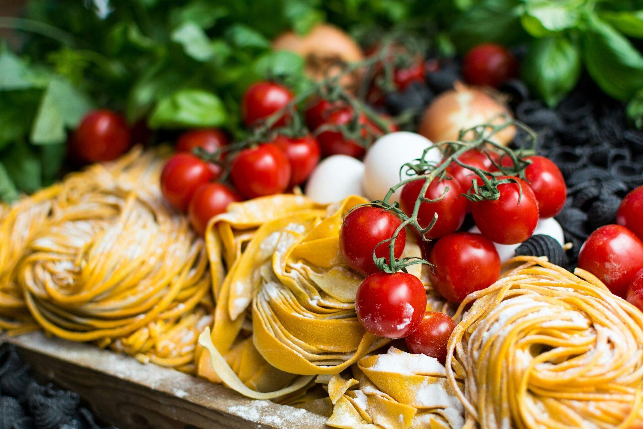 Expositor colorido de pasta fresca y tomates cherry en un mercado mediterráneo típico
