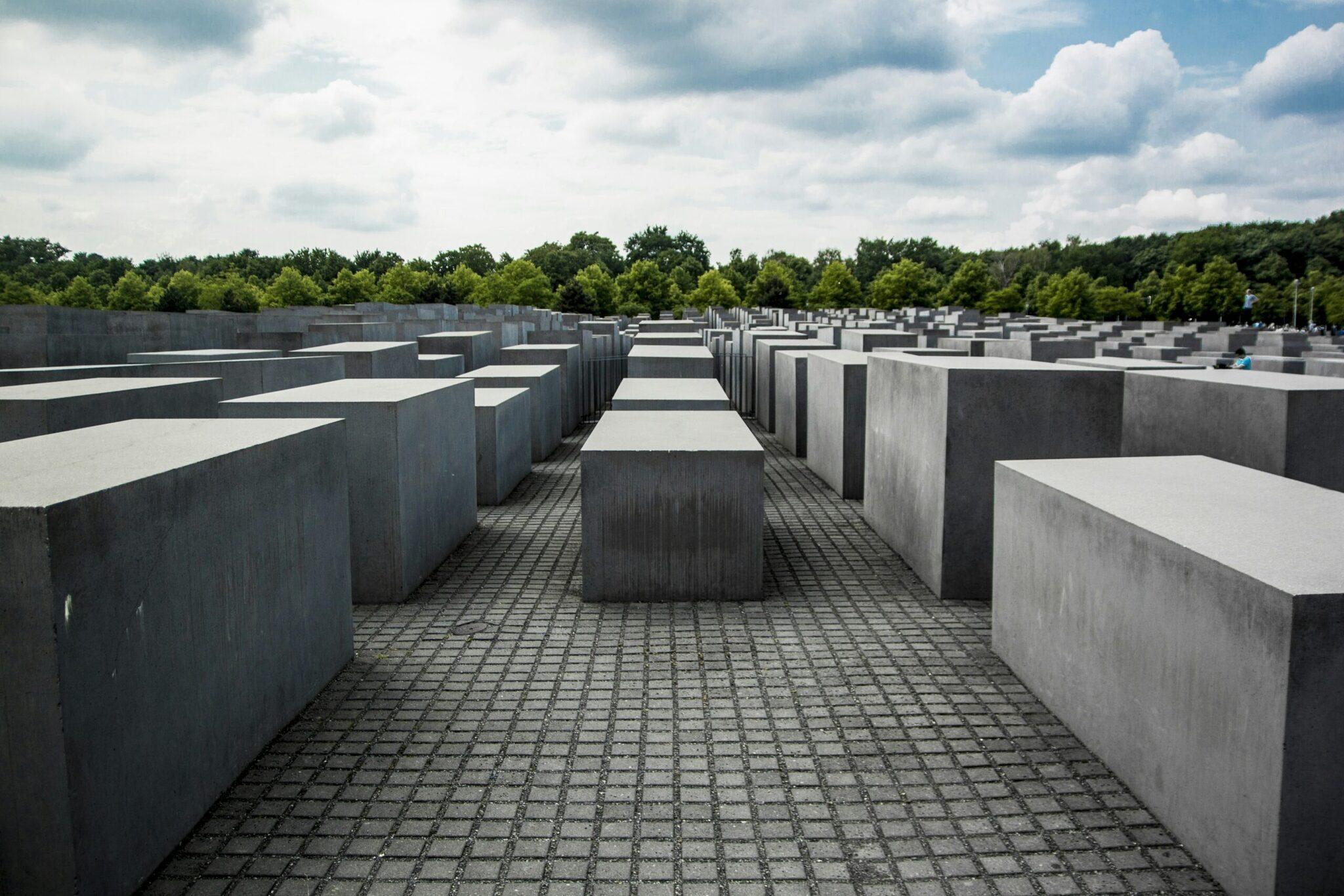Memorial a las víctimas del Holocausto con sus bloques de hormigón gris alineados bajo un cielo nublado y vegetación verde al fondo