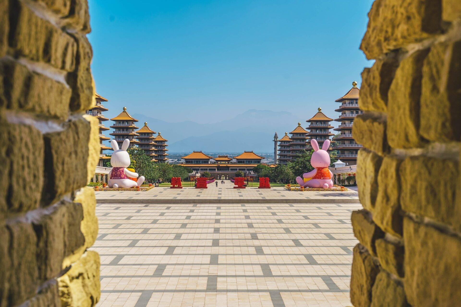 Vista su un cortile di tempio asiatico con pagode dorate incorniciate da muri verdi scolpiti
