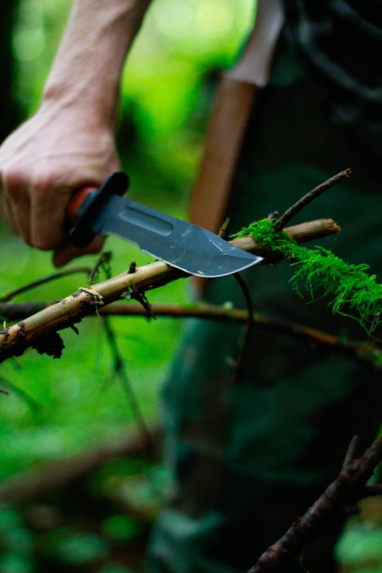 Wanderer in der Wildnis, der auf dem Smartphone die SAS Survival Guide App nach Überlebenstipps durchsucht