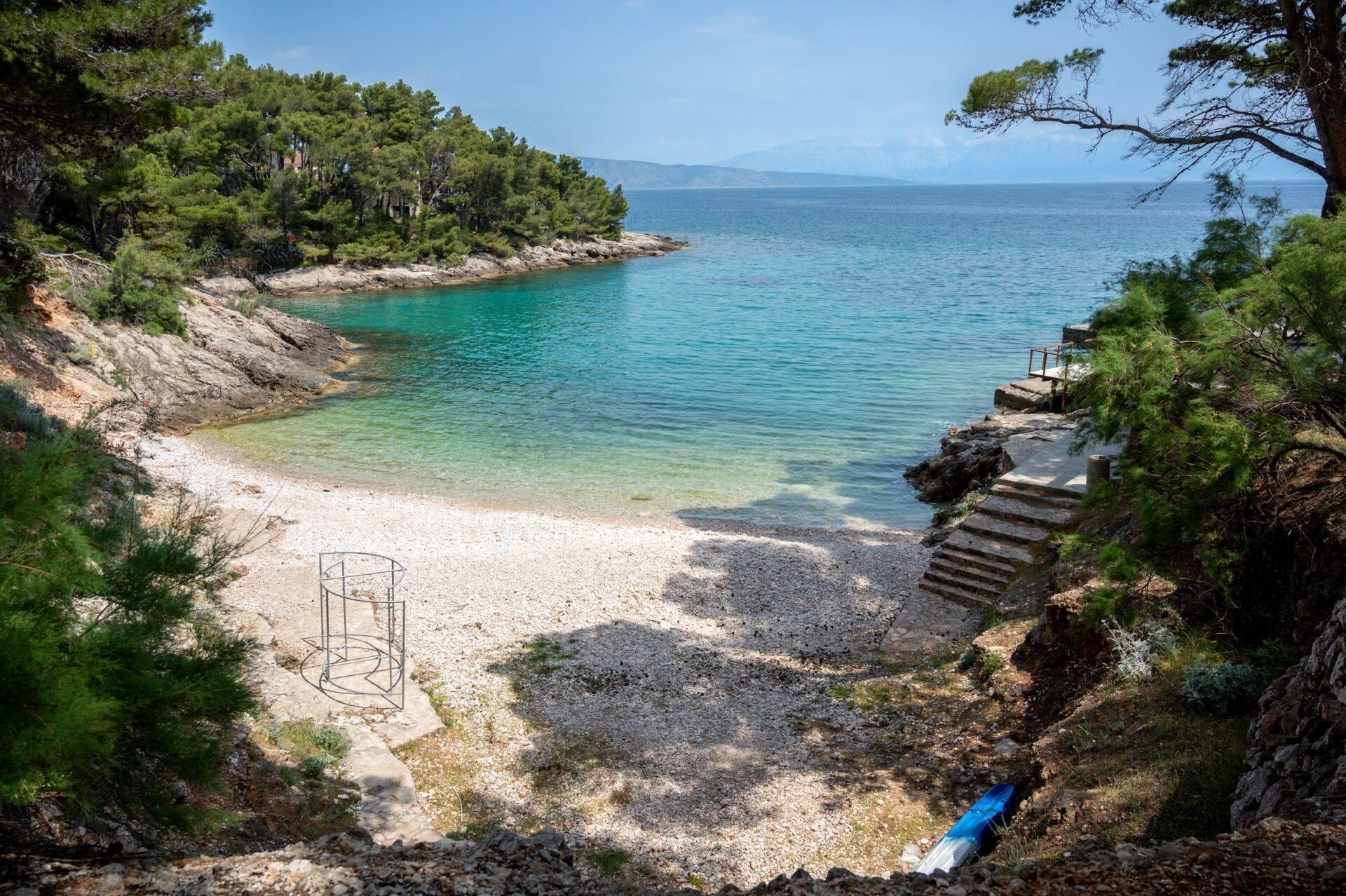 Piccola cala mediterranea con spiaggia di ciottoli, acque turchesi e scogliere boscose in Croazia