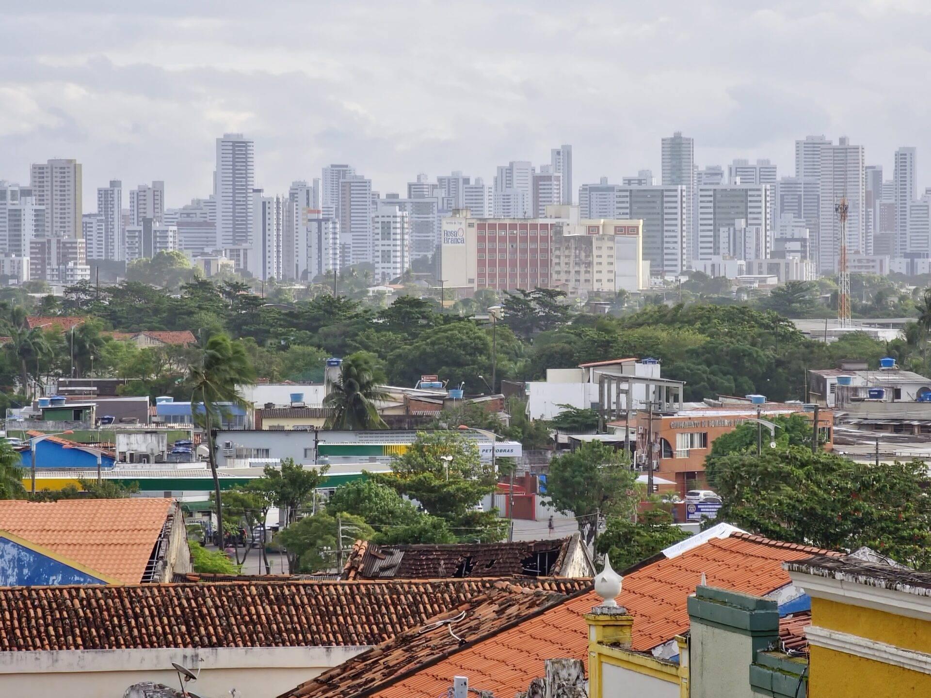 Blick über farbenfrohe Hausdächer eines Wohnviertels, dahinter die Hochhäuser einer brasilianischen Großstadt