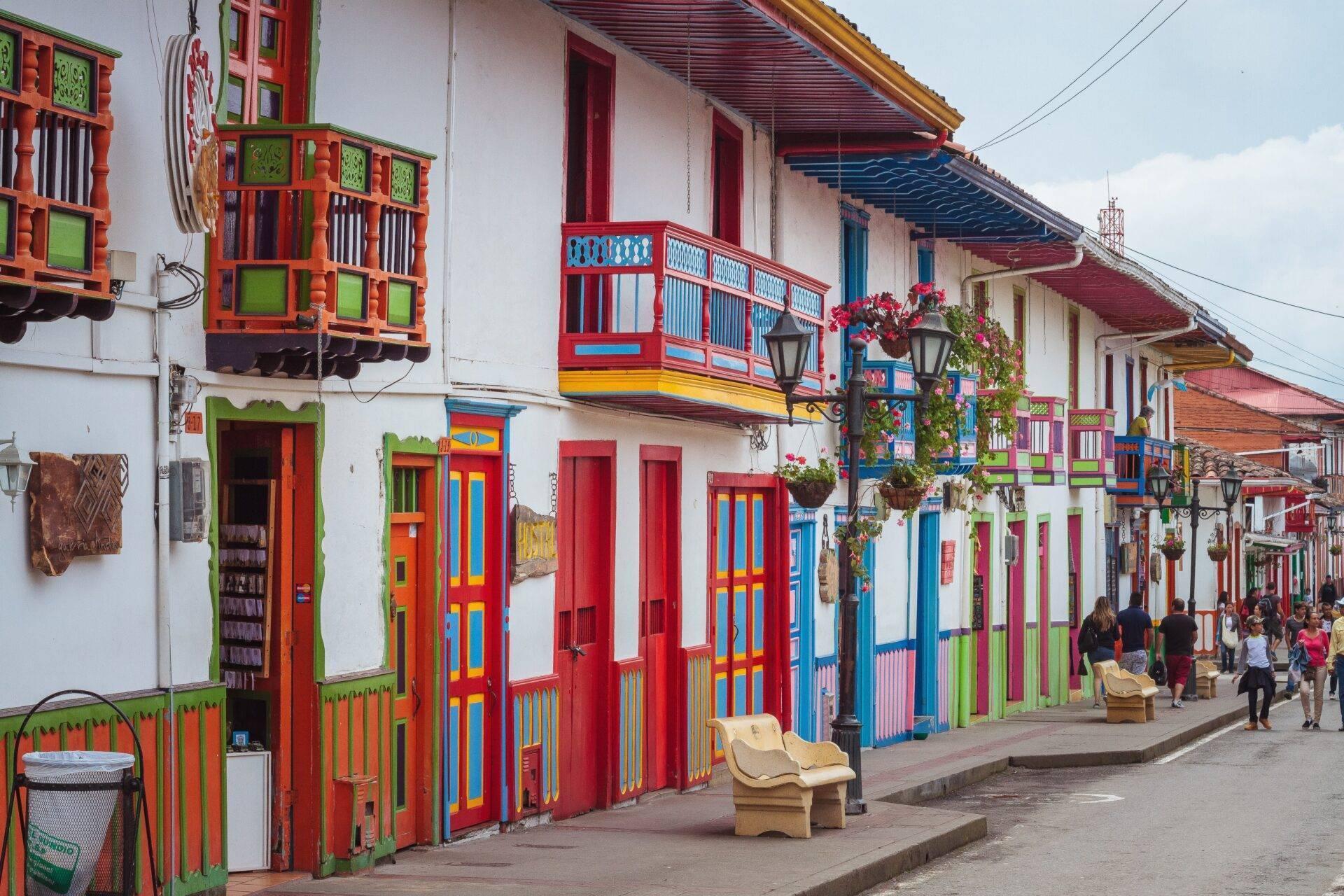 Calle colonial pintoresca con casas de colores de fachadas roja, azul y verde con balcones ornamentados típicos de la arquitectura colonial andina