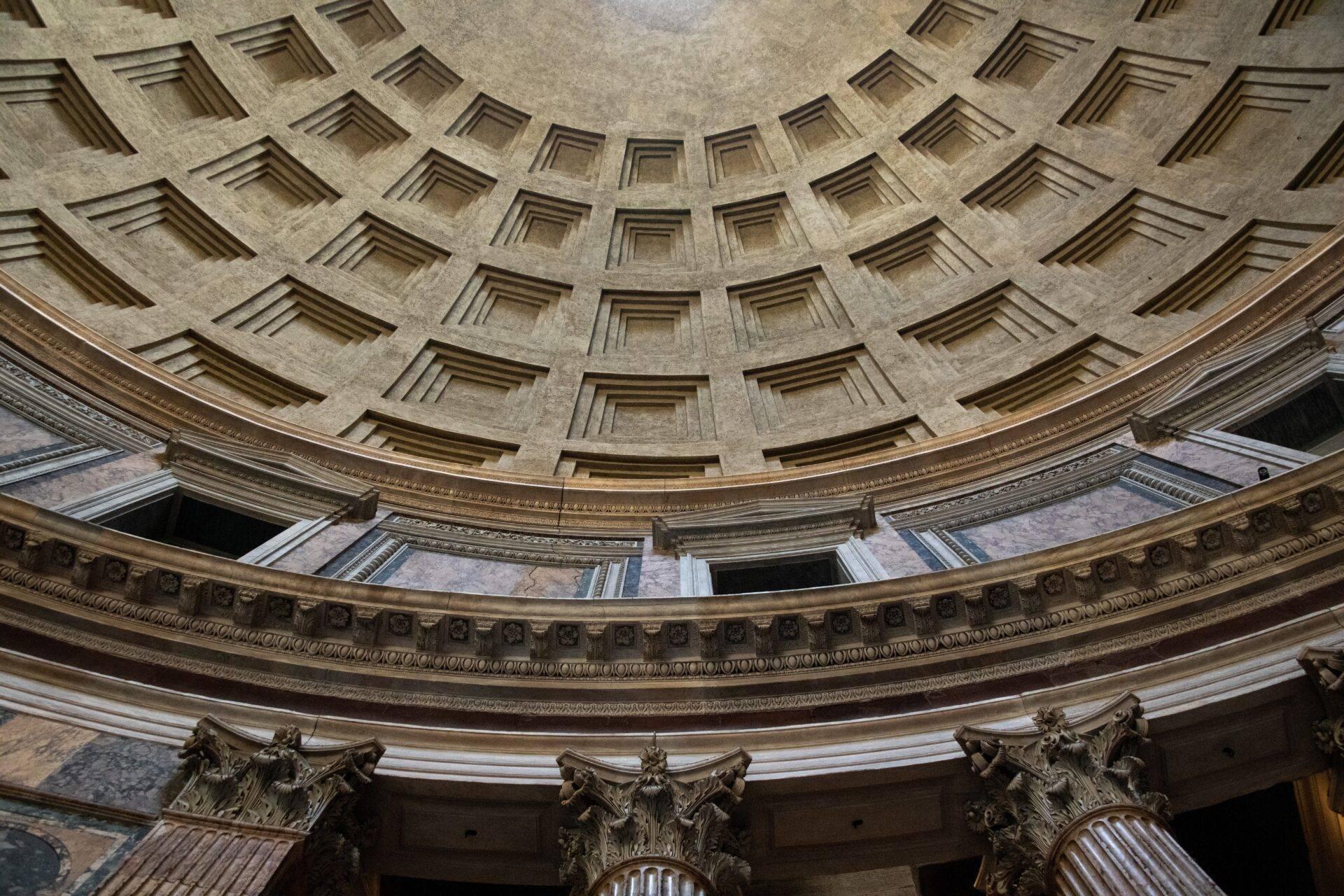 Interior of a monumental building with a coffered dome and gilded Corinthian columns in classical architecture
