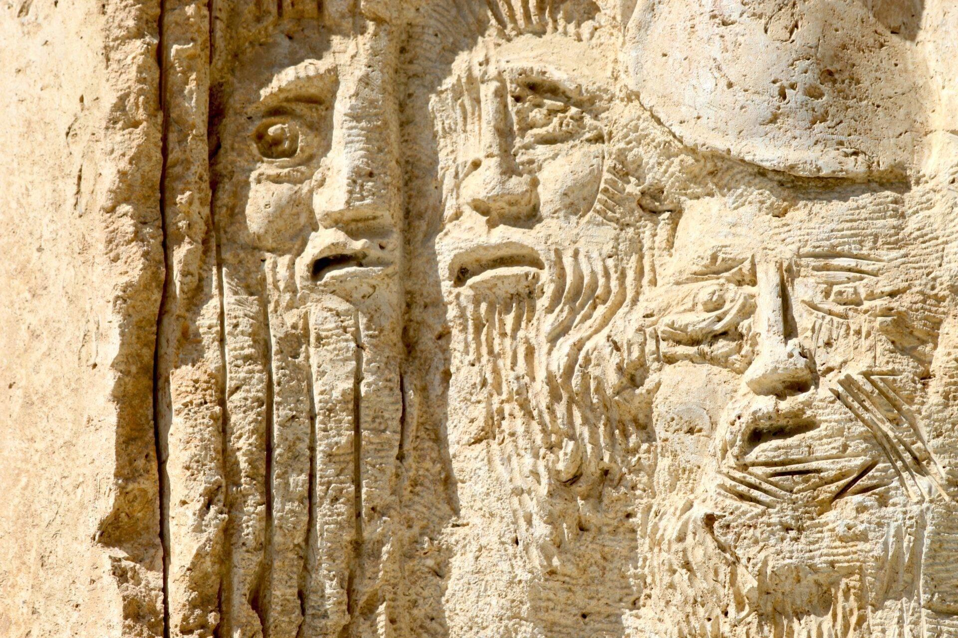 Bajorrelieve en piedra caliza con figuras humanas e inscripciones antiguas grabadas en la fachada de un templo histórico