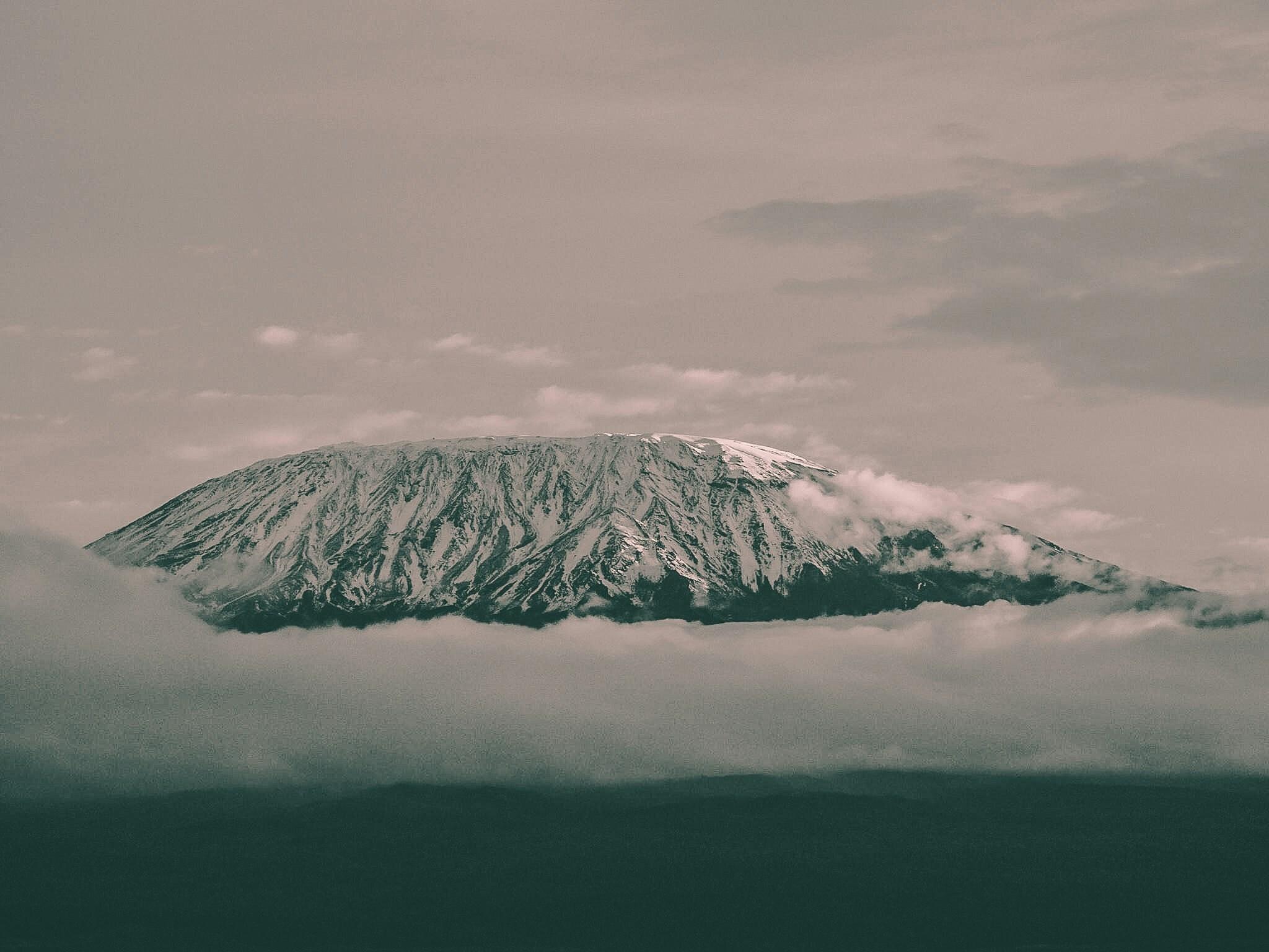 Un volcán nevado emerge entre las nubes en una atmósfera brumosa y misteriosa