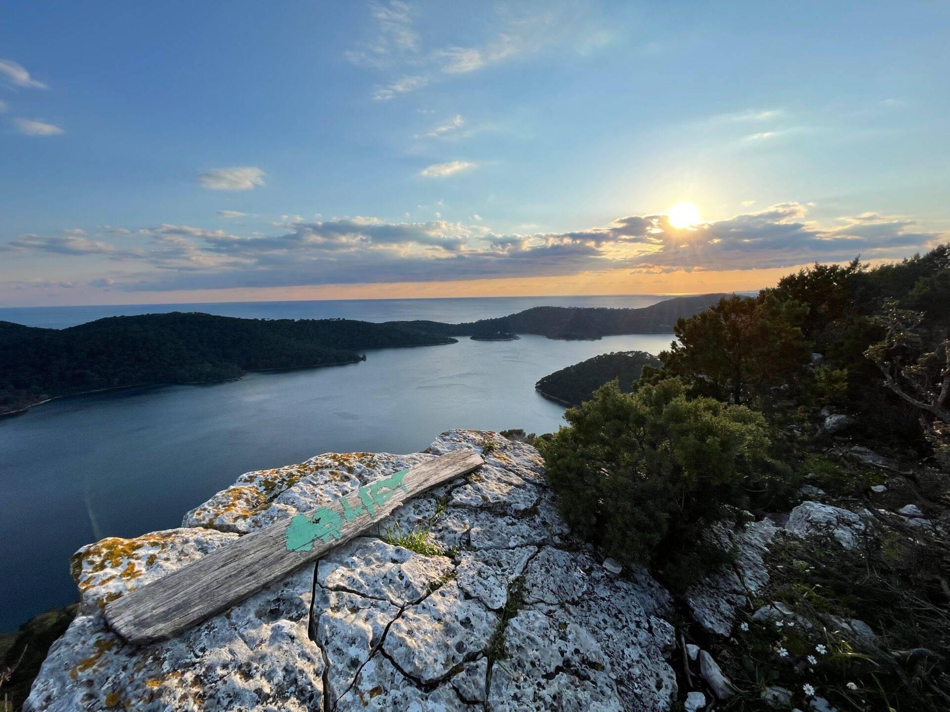 Vista panoramica al tramonto su un litorale mediterraneo con baie boscose e rocce costiere