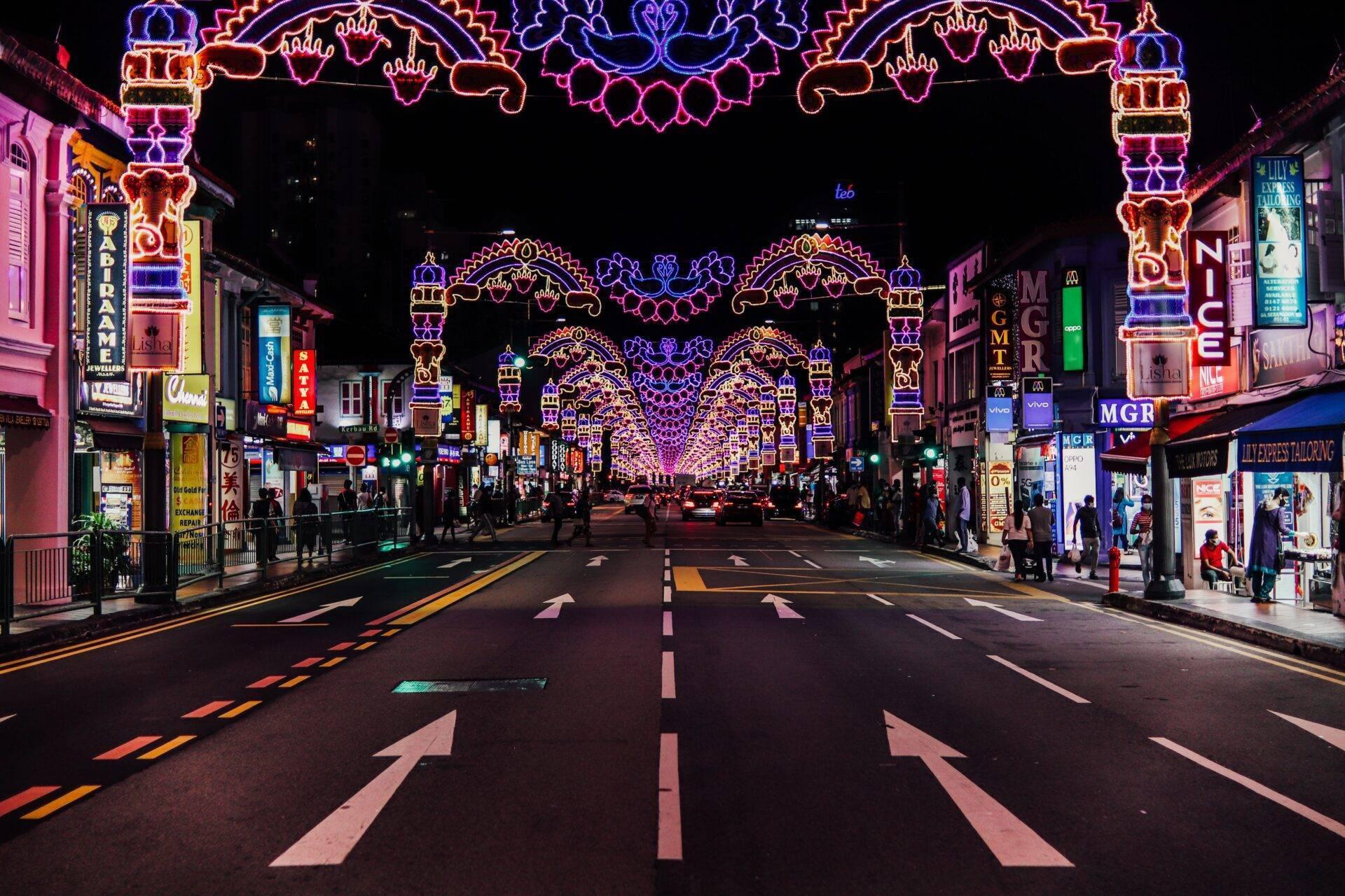 Eine asiatische Einkaufsstraße bei Nacht, erleuchtet von bunten Neonlichtern unter dekorativen Bögen