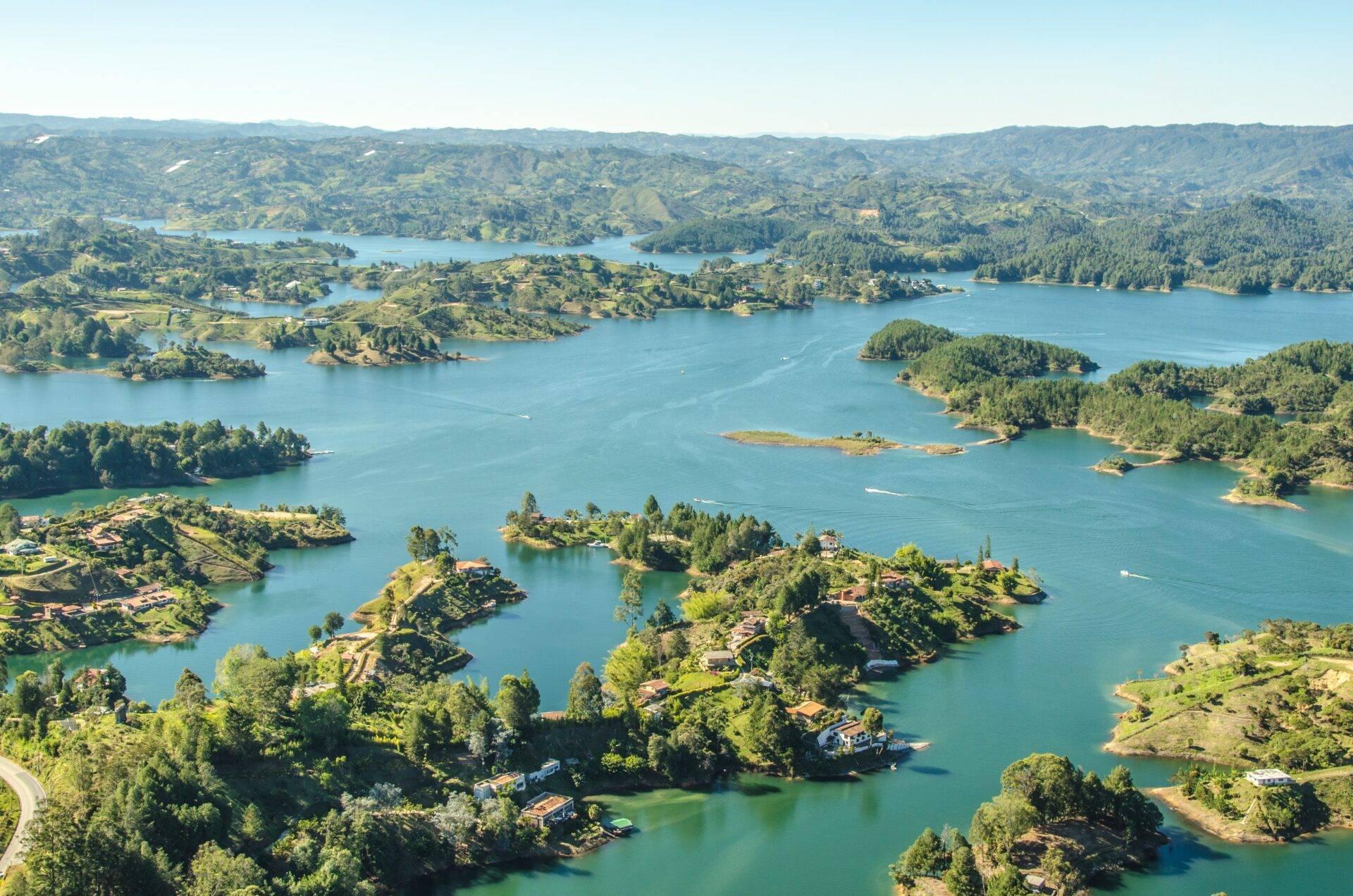 Vista aérea de un vasto sistema de lagos montañosos con islas boscosas y casas dispersas en una región tropical
