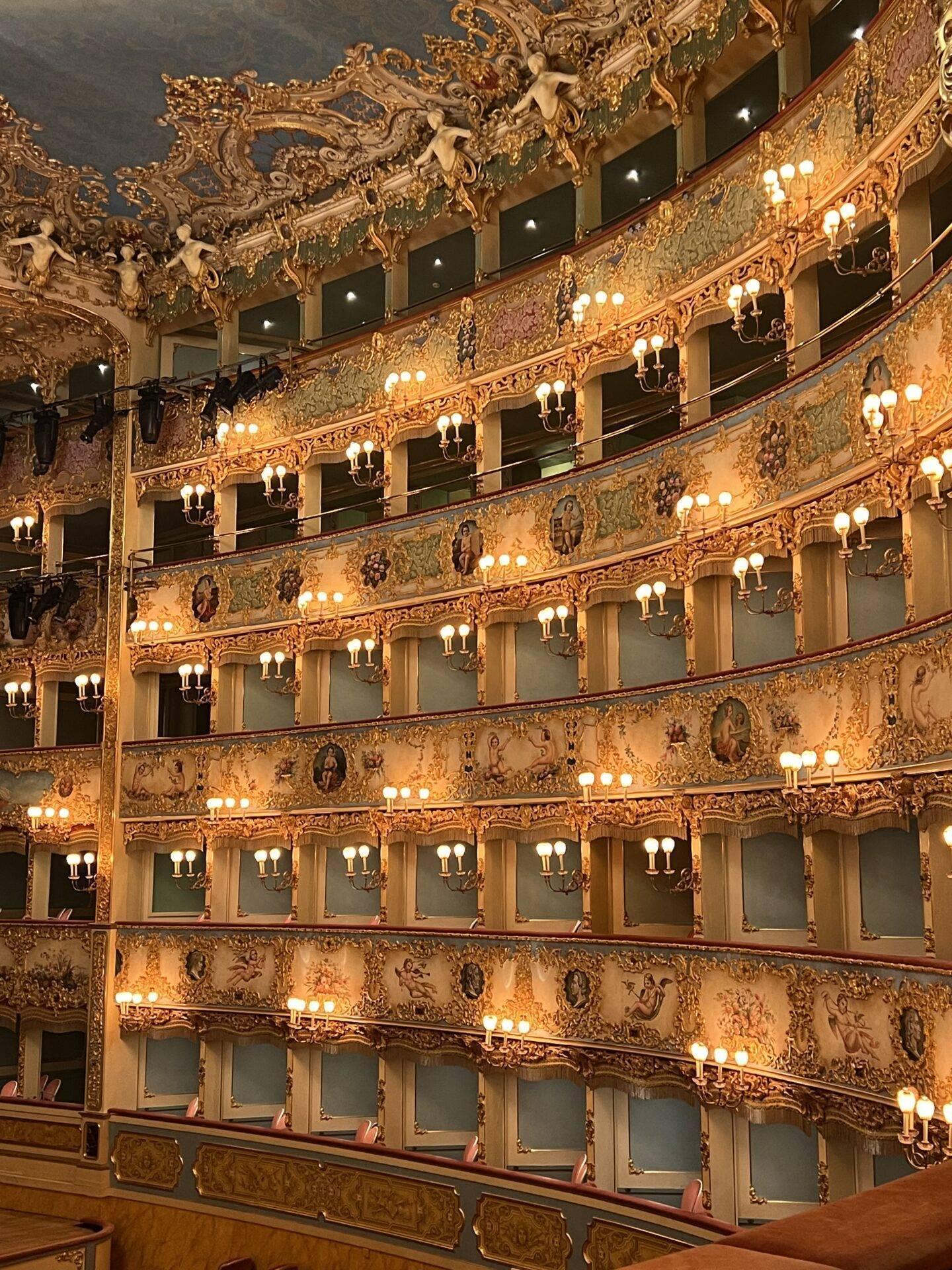 Interno sontuoso di un teatro barocco con balconi dorati ornati e applique luminose