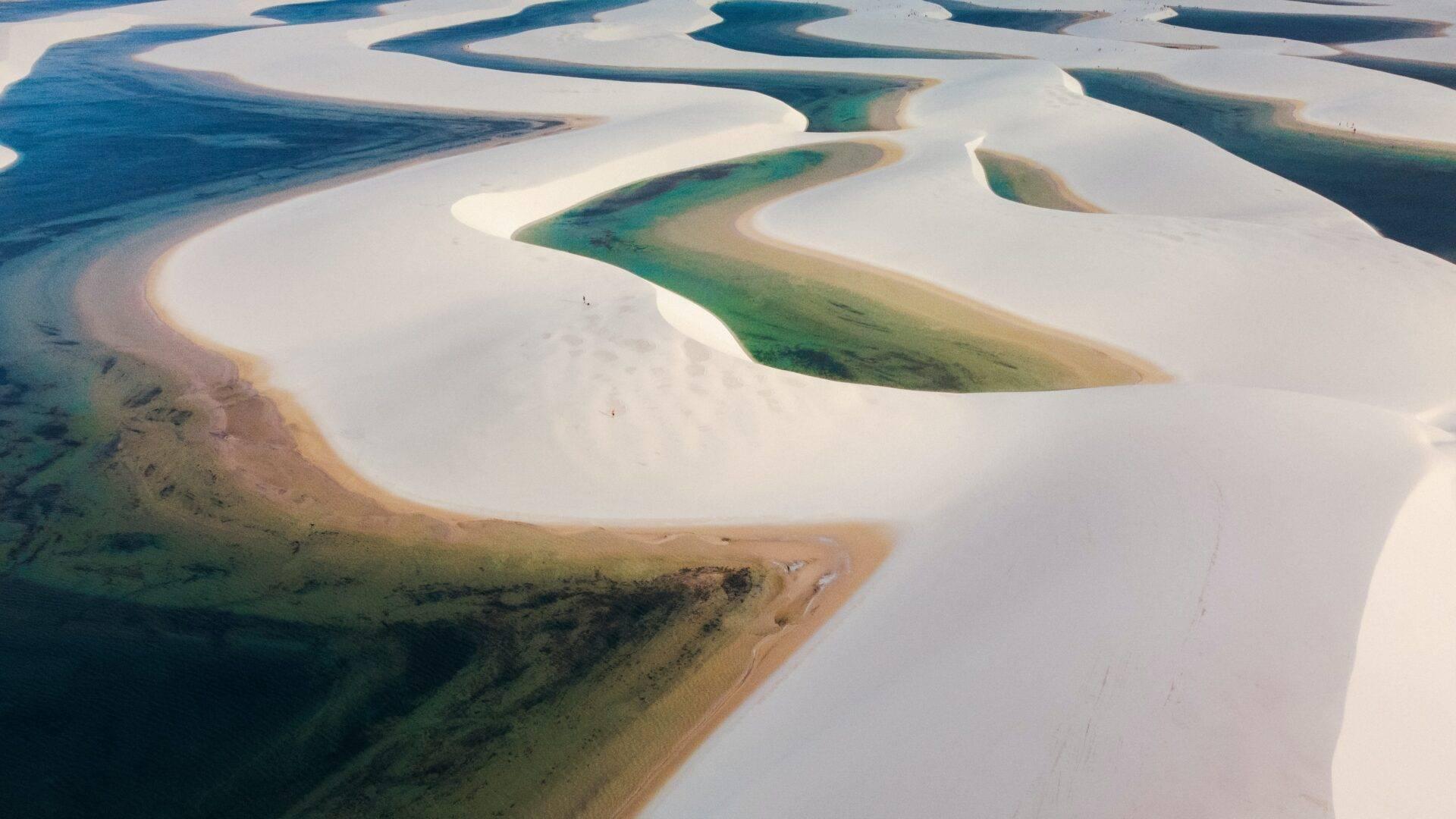 Vista aerea di laghi con dune di sabbia bianca e acque turchesi dalle tonalità blu-verde in un paesaggio desertico costiero