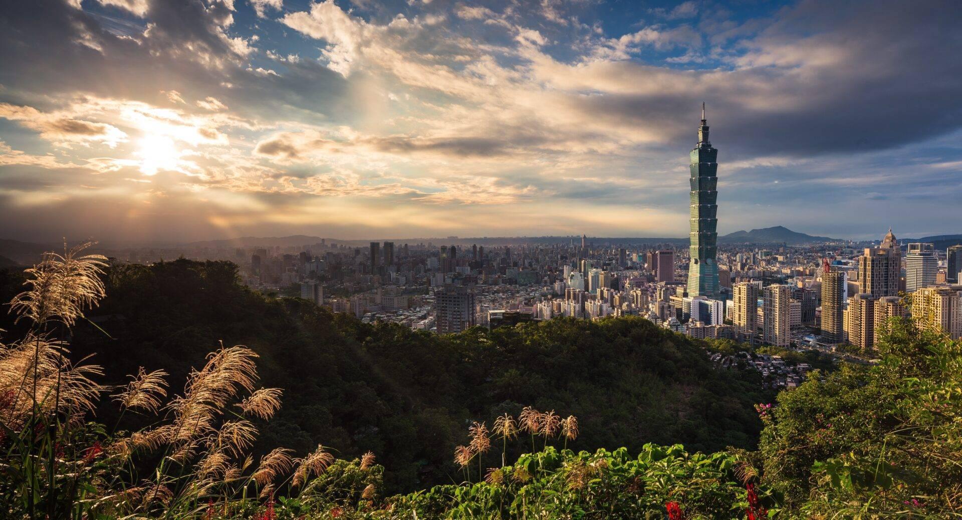 Vista panoramica di una metropoli asiatica densamente costruita con una torre distintiva e montagne sullo sfondo