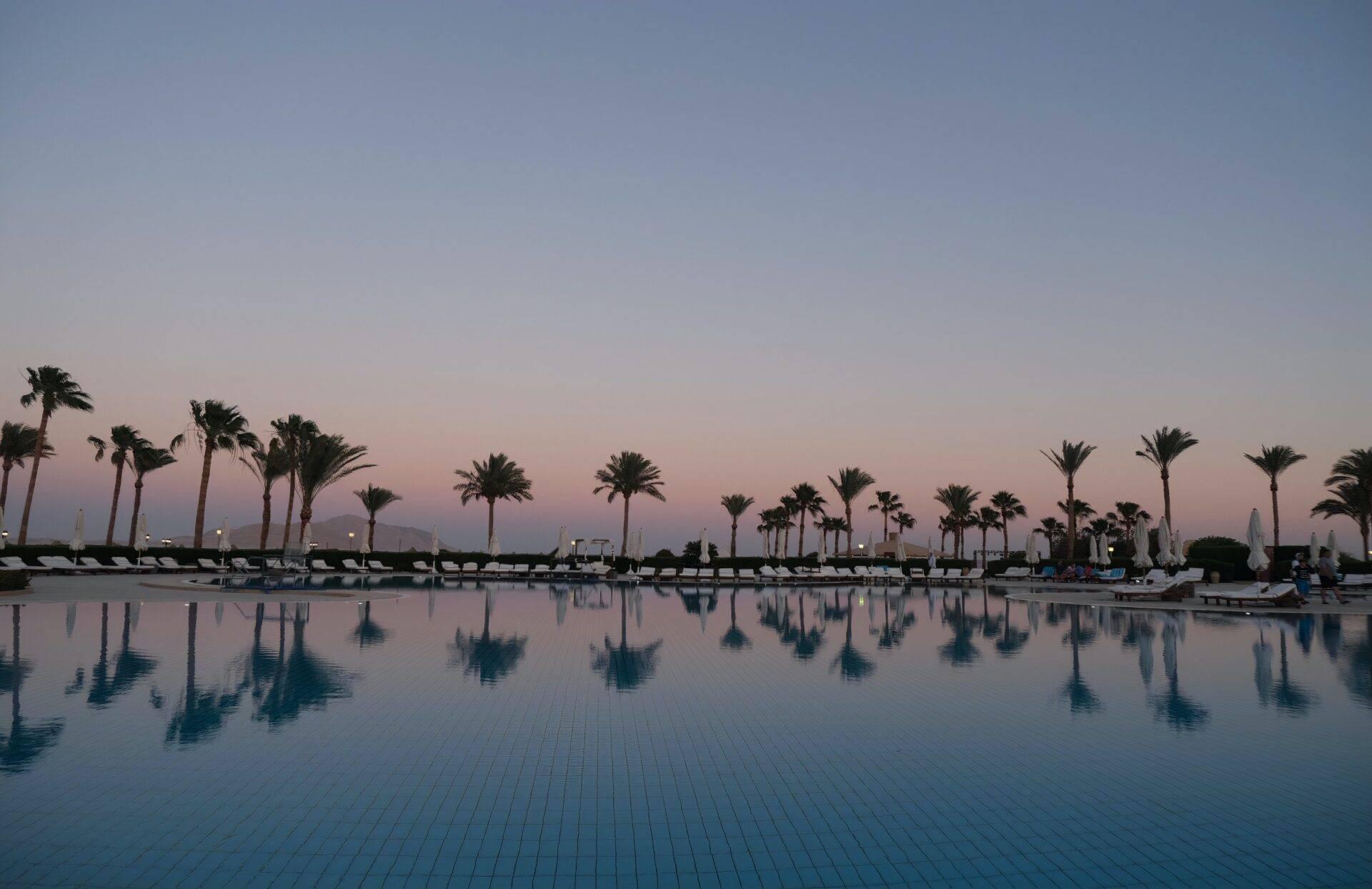 Una piscina di lusso al tramonto fiancheggiata da palme e lettini in Egitto